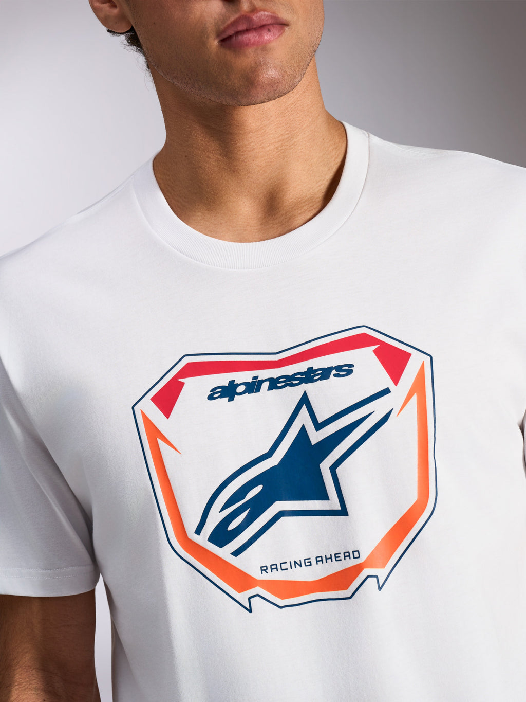 Alpinestars Plate CSF Tee, kurzärmeliges T-Shirt, Weiß, MX-Plattengrafik auf der Vorderseite mit blauem Astars-Logo und „Racing Ahead“-Schriftzug, orangefarbene und rote Akzente, lässige Motorsport-Sportbekleidung