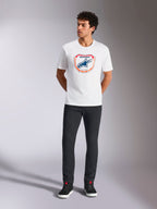 Alpinestars Plate CSF Tee, Kurzarm-T-Shirt, Weiß, mit einer Astars MX-Plattengrafik auf der Vorderseite mit orangefarbenen und blauen Akzenten, getragen von einem Model mit schwarzer Hose und Sneakern, legere Motorsport-Streetwear