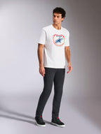 Alpinestars Plate CSF Tee, Kurzarm-T-Shirt, Weiß, mit einer Astars MX Plattengrafik in Blau und Orange auf der Vorderseite, lässige motorsport-inspirierte Streetwear getragen mit dunkler Hose und High-Top-Sneakern