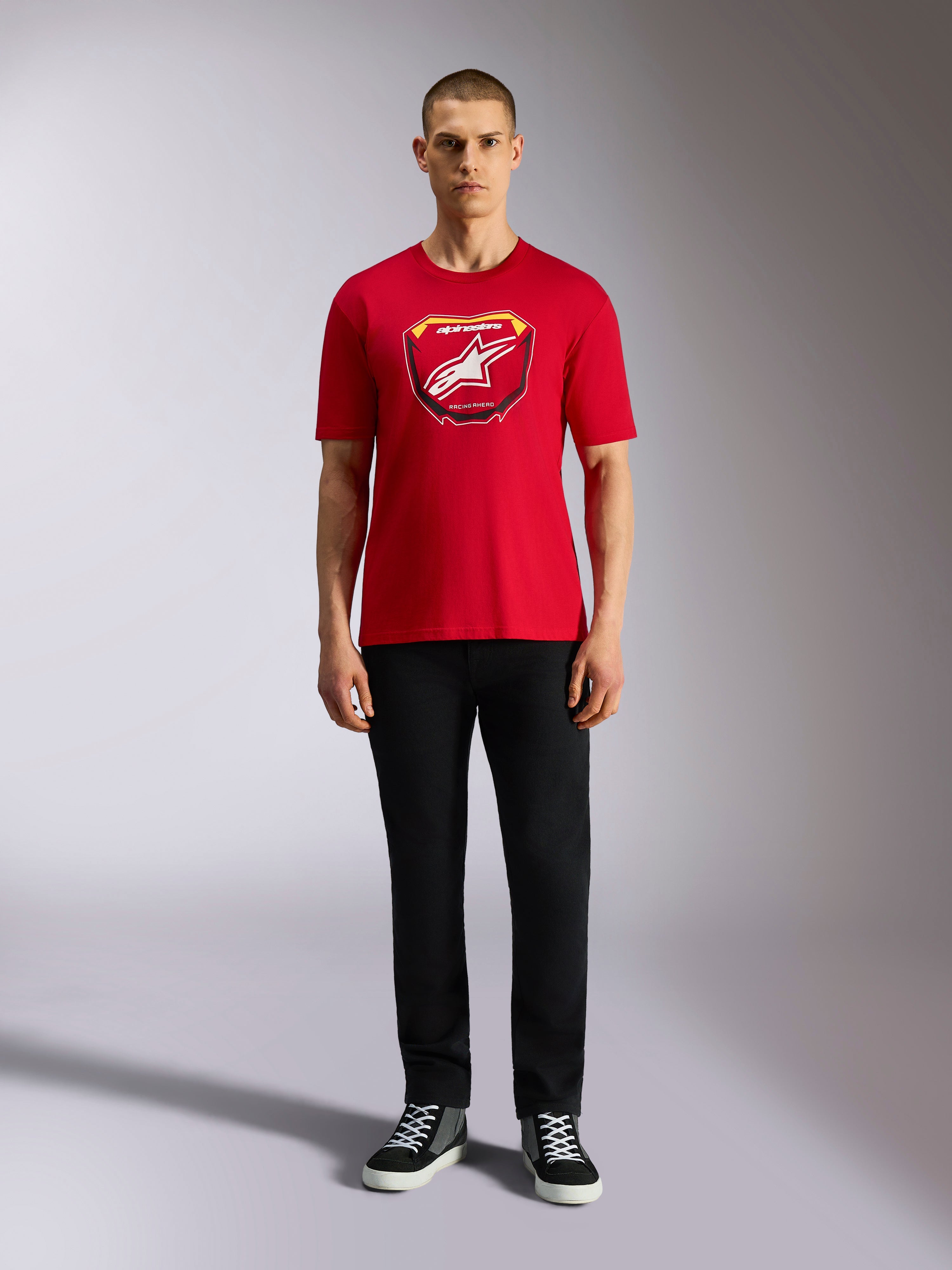 Alpinestars Plate CSF Tee, kurzärmeliges T-Shirt, Rot, MX-Plattengrafik auf der Vorderseite mit weißem Stern-Logo, kombiniert mit schwarzer Hose und Sneakern, lässige Motorsport-Streetwear