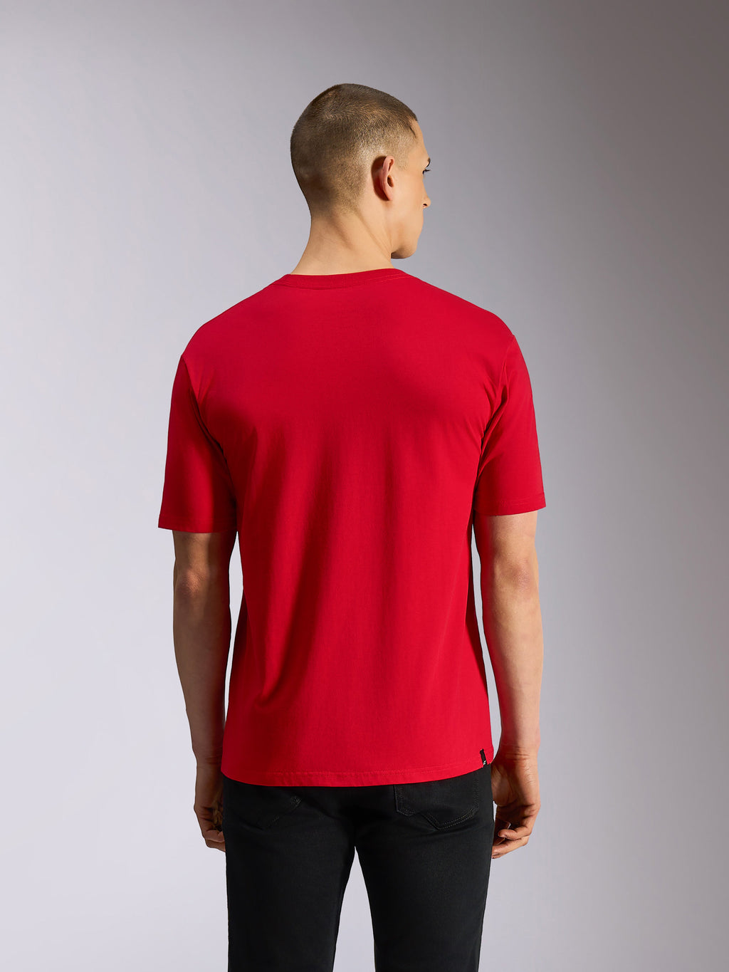 Alpinestars Plate CSF Tee, Kurzarm-T-Shirt, Rot, Rückansicht mit schlichtem rotem Stoff und lässiger Passform, getragen mit schwarzer Hose, Motorsport-inspirierte Streetwear