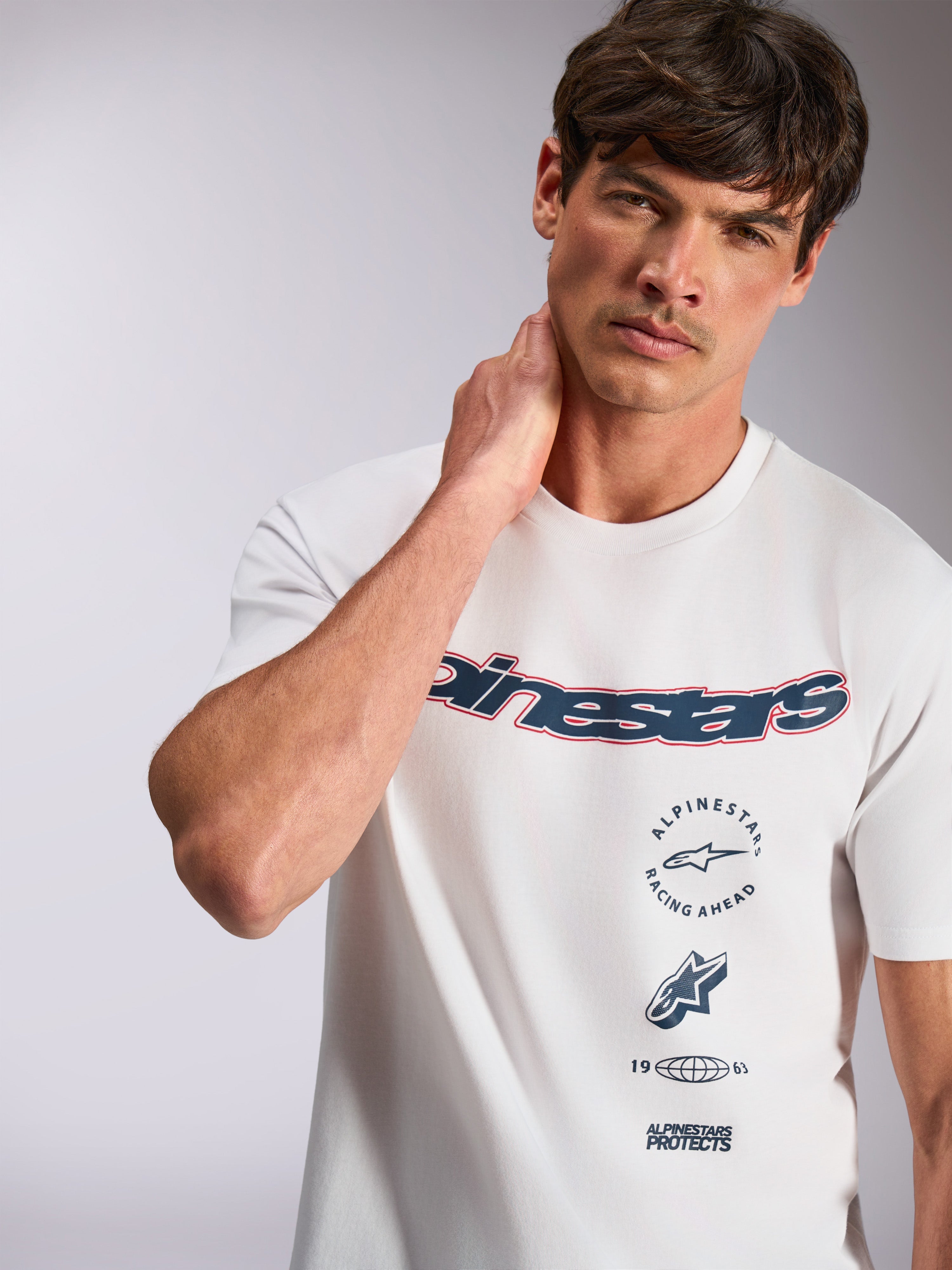 Alpinestars Abus CSF Tee, kurzärmeliges T-Shirt, Weiß, mit marineblauem, geschwungenem Alpinestars-Logo mit roter Umrandung und mehrfach gestapelten Grafiken, lässige Motorsport-Streetwear