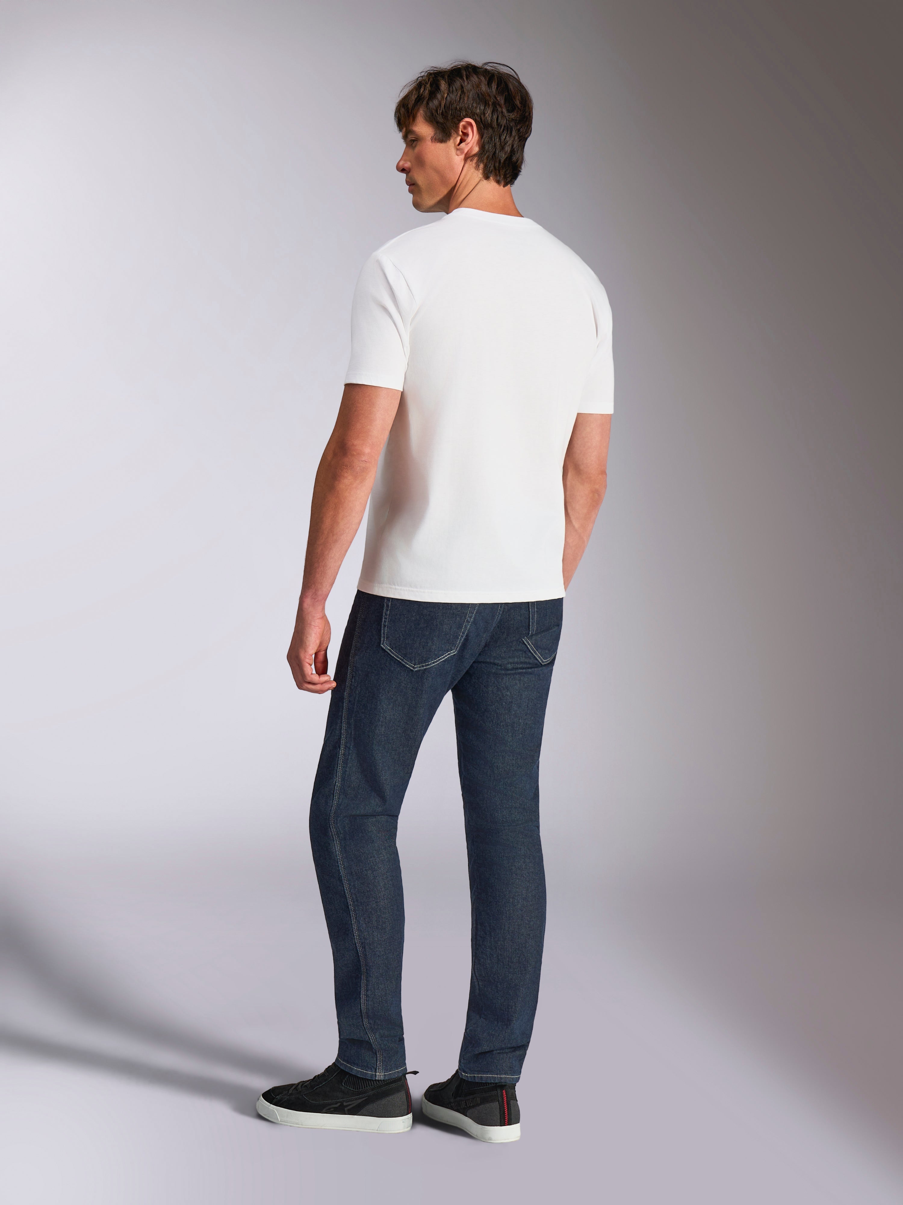 Alpinestars Abus CSF Tee, Kurzarm-T-Shirt, Weiß, Rückansicht an einem Modell in dunkelblauen Jeans und schwarzen Sneakern, lässiges motorsport-inspiriertes Design
