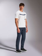 Alpinestars Abus CSF Tee, kurzärmeliges T-Shirt, Weiß, Design mit mehreren gestapelten, gebogenen Alpinestars-Logos, getragen von einem männlichen Model mit dunkelblauen Jeans und schwarzen Sneakern, lässige Motorsport-Streetwear