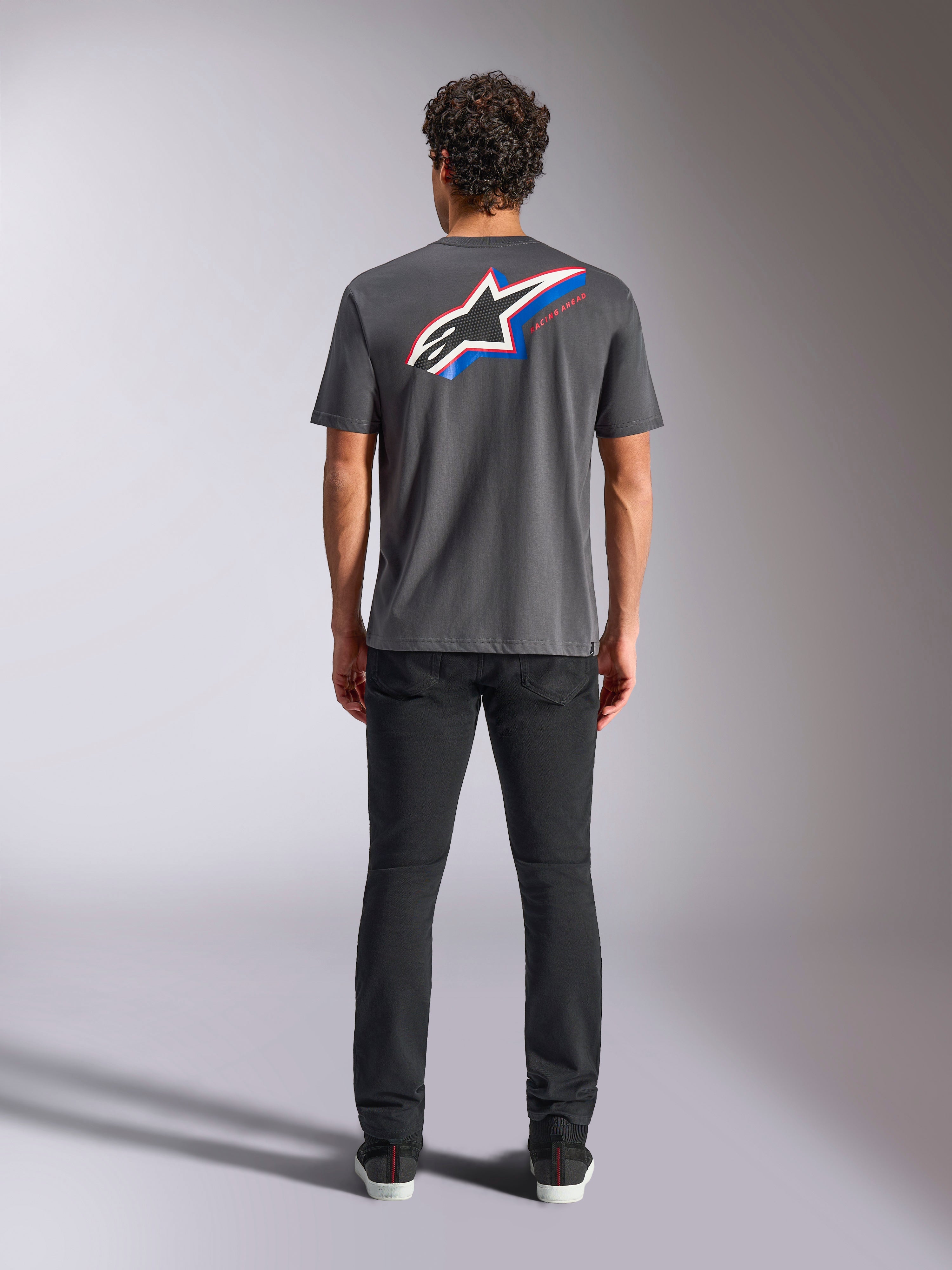 Alpinestars Angler CSF Tee, Kurzarm-T-Shirt, Charcoal, Großes mehrfarbiges Astars-Logo auf der Rückseite mit roten und blauen Akzenten, Rückansicht am Model, lässige Motorsport-Streetwear
