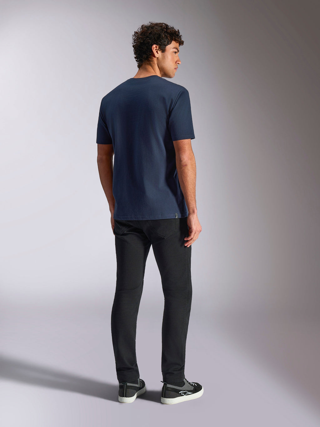 Alpinestars Trifecta CSF Tee, Kurzarm-T-Shirt, Marineblau, Rückansicht, lässige Sportbekleidung, getragen mit schwarzer Hose und schwarzen Sneakern