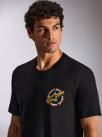 Alpinestars Aorbit CSF Tee, kurzärmeliges T-Shirt, Schwarz, kreisförmige „Always Fast Made to Last“-Brustgrafik mit gelbem Astars-Logo, von einem Model getragen, Casual Motorsport Streetwear