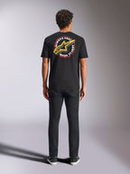 Alpinestars Aorbit CSF Tee, kurzärmeliges T-Shirt, Schwarz, Rückansicht an einem Model mit schwarzer Hose, mit großer „Always Fast Made to Last“-Grafik und gelbem Astars-Logo, lässige Motorsport-Streetwear
