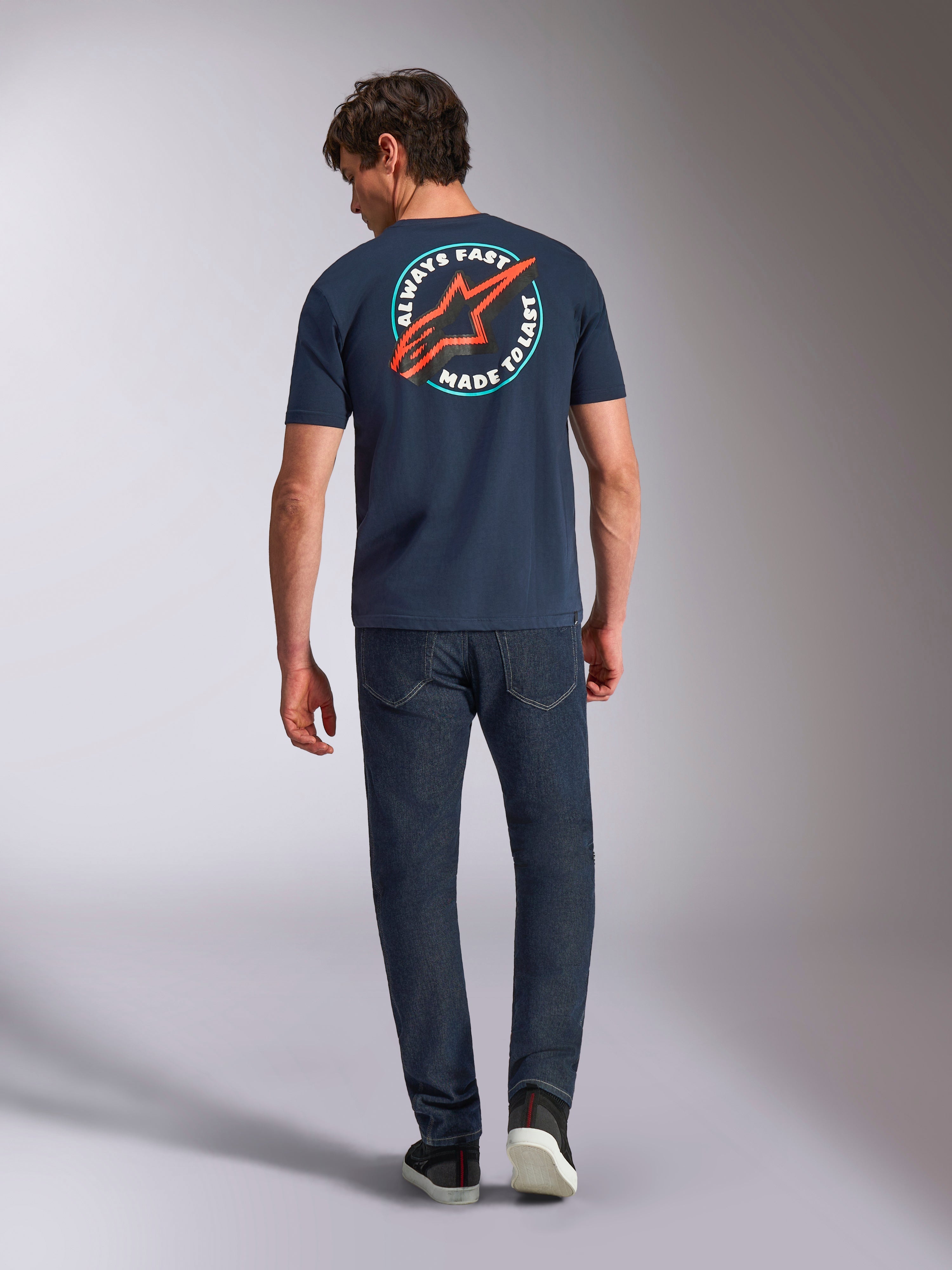 Alpinestars Aorbit CSF Tee, kurzärmeliges T-Shirt, Navy, Rückansicht am Modell mit großer kreisförmiger Grafik, rotem Astars-Logo und „Always Fast Made to Last“-Schriftzug, lässige Motorsport-Streetwear