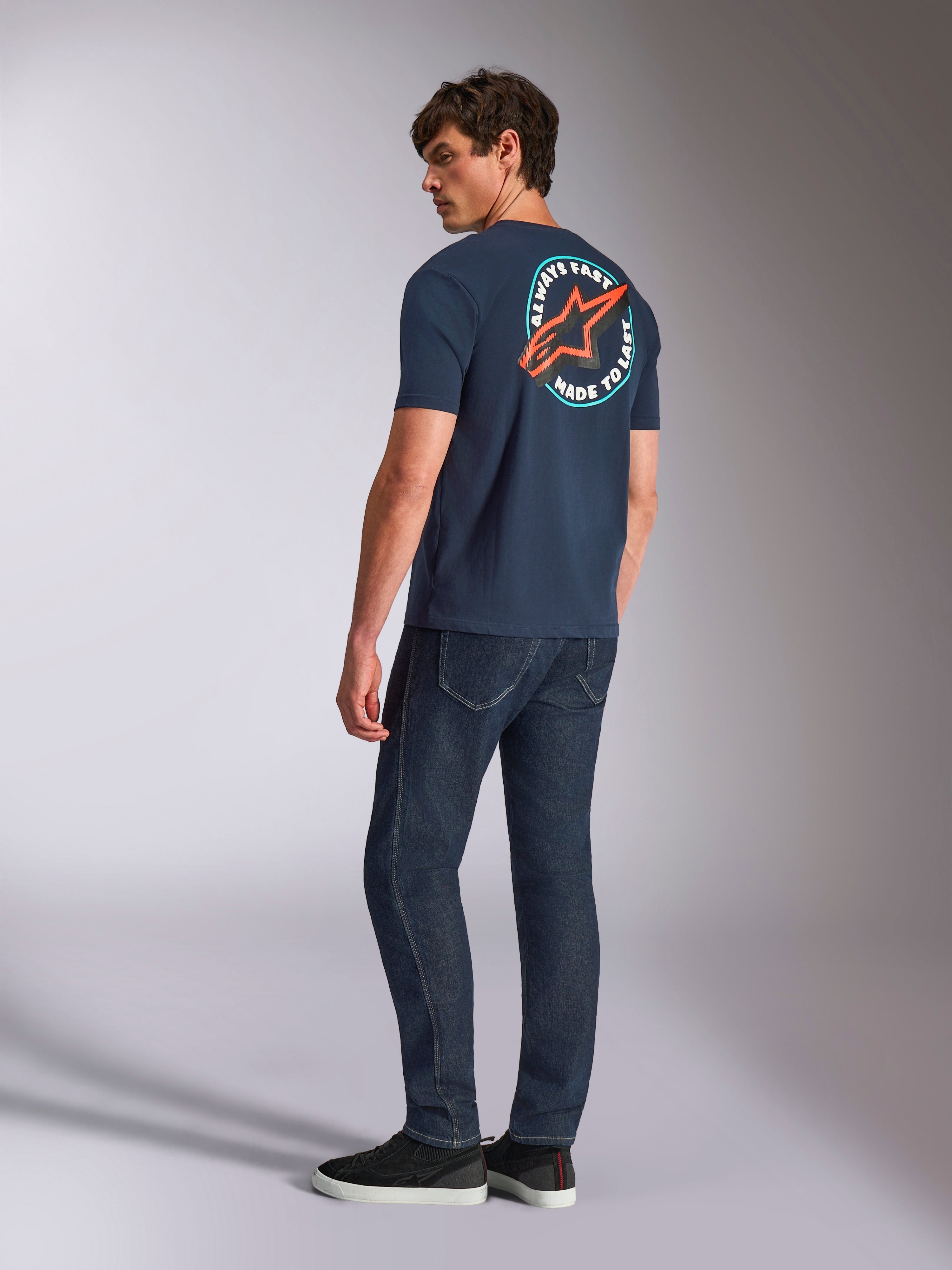 Alpinestars Aorbit CSF Tee, kurzärmeliges T-Shirt, Navy-Blau, Rückansicht am Modell mit großem kreisförmigem Astars-Logo und „Always Fast Made to Last“-Grafik, lässige, vom Motorsport inspirierte Streetwear