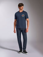 Alpinestars Aorbit CSF Tee, kurzärmeliges T-Shirt, Navy, kreisförmige Brustgrafik mit „Always Fast Made to Last“-Text, getragen mit dunkler Jeans und Sneakern, lässige Motorsport-Lifestyle-Bekleidung