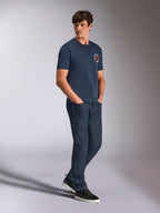 Alpinestars Aorbit CSF Tee, Kurzarm-T-Shirt, Navy, mit kreisförmigem orangefarbenem und weißem Astars-Logo und „Always Fast Made to Last“-Grafik, getragen von einem Mann mit dunklen Denim-Jeans und schwarzen Sneakern, lässige motorsport-inspirierte Streetwear
