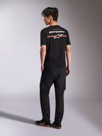 Alpinestars Lanes CSF Tee, schwarzes Kurzarm-T-Shirt, Rückansicht mit weißem Alpinestars-Logo sowie roten, orangen und gelben Streifengrafiken, lässige Motorsport-Streetwear kombiniert mit einer schwarzen Cargo-Hose
