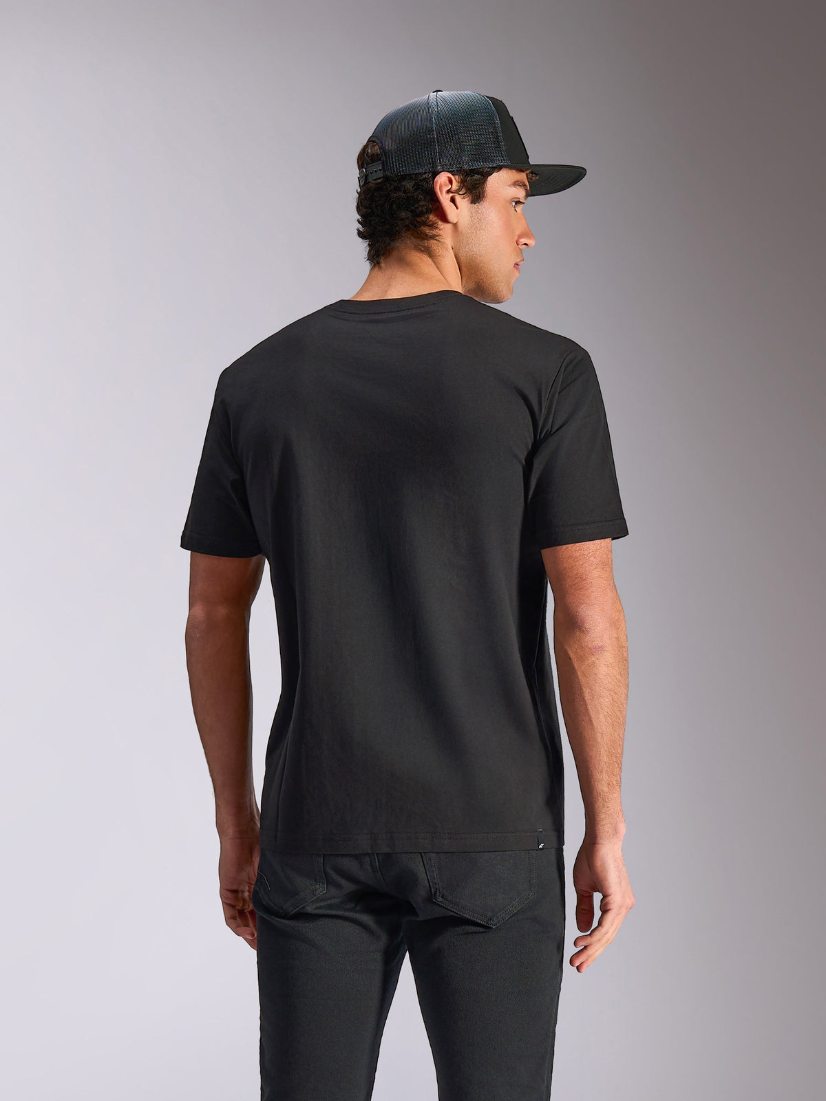 Alpinestars Verdure Camo CSF T-Shirt, kurzärmeliges T-Shirt, Schwarz, Rückansicht, kombiniert mit Mesh-Cap und schwarzer Hose, Casual Motorsport Streetwear