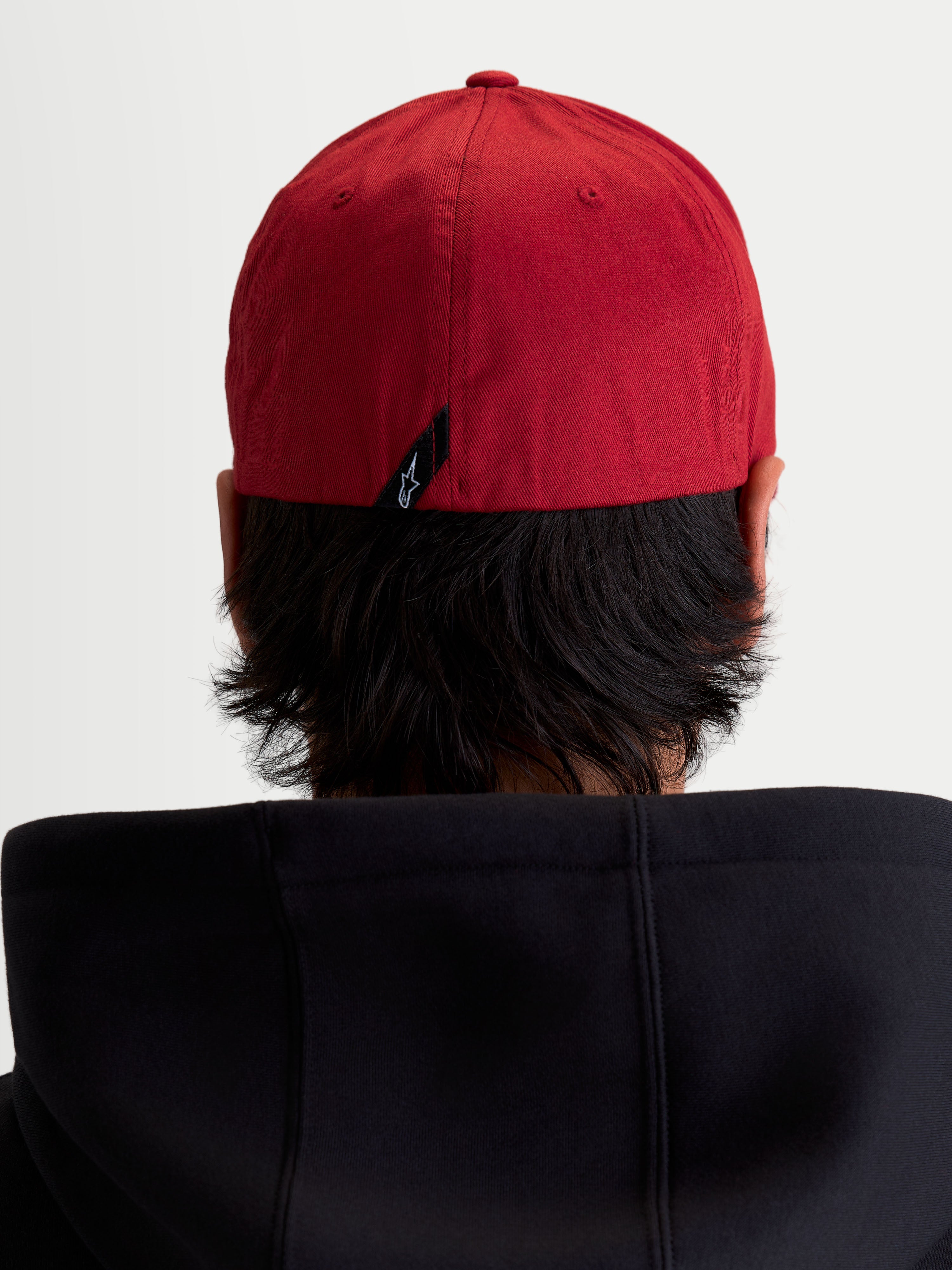 Alpinestars Pivot Kappe, Sportswear Baseball-Kappe, Dunkelrot, Rückansicht am Modell mit Flex-Rückseite und kleinem Astars Logo-Etikett auf der Rückseite.