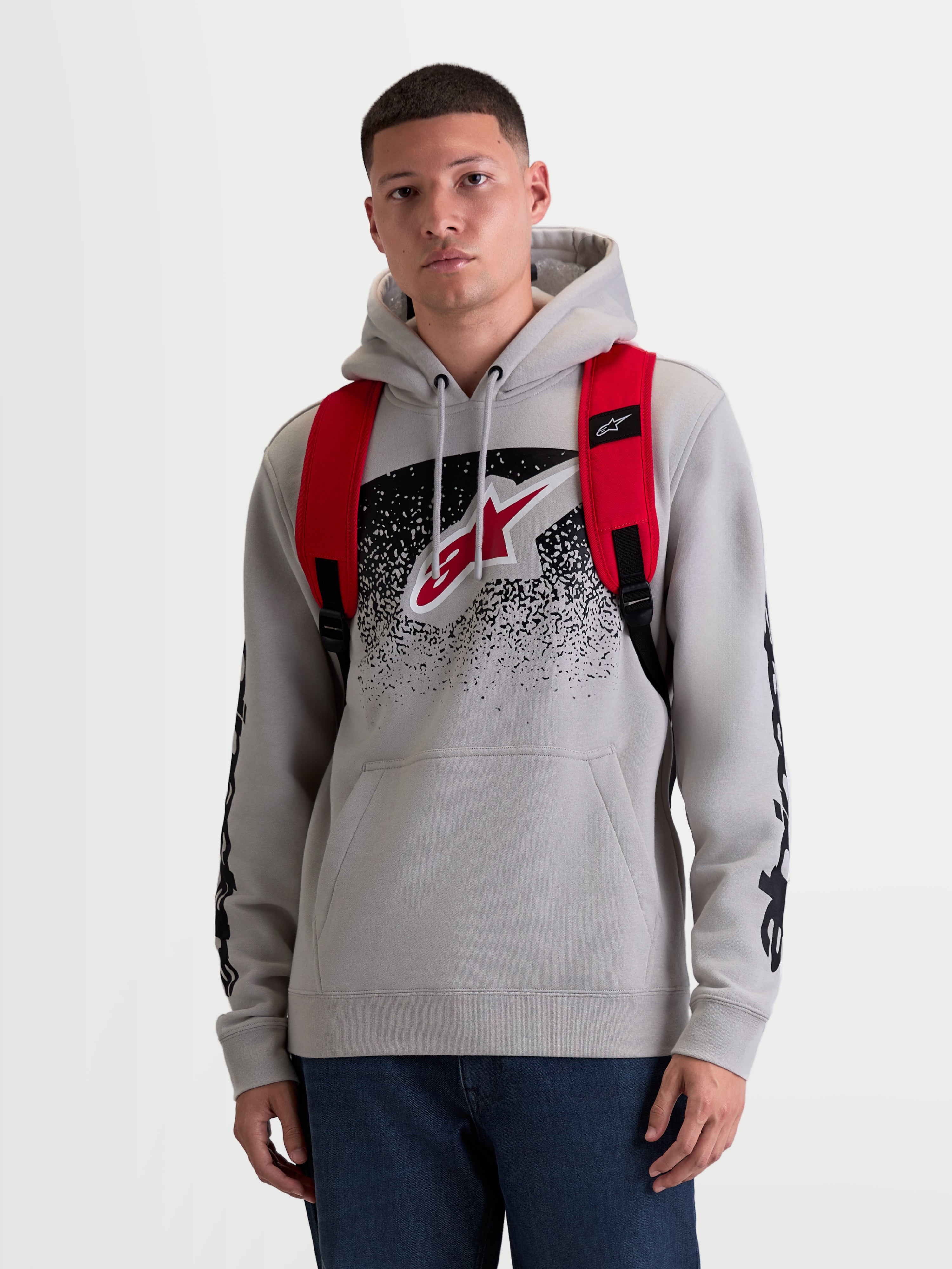 Alpinestars GFX Boss Rucksack, urbaner Sport-Tagesrucksack für Herren und Damen, Rot und Schwarz, strapazierfähiges 600D Polyester, Vorderansicht am Modell mit verstellbaren Air-Mesh-Schultergurten und erhabenem Silikon-Branding, 20L Kapazität.