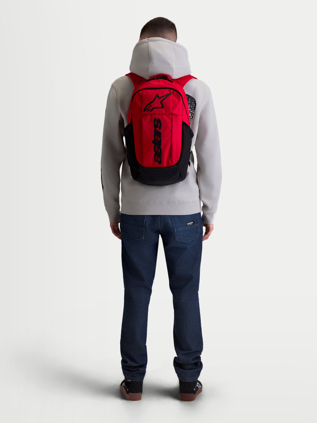 Alpinestars GFX Boss Rucksack, Urban Sportswear Tagesrucksack, Rot und Schwarz, 20L Kapazität, Rückansicht am Modell, aus robustem 600D Polyester mit internem Laptopfach und gepolsterten Air-Mesh-Schultergurten.