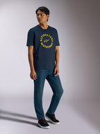 Alpinestars MX CSF Tee, Kurzarm-T-Shirt, Navy, gelbe kreisförmige Alpinestars Motocross-Grafik, getragen von einem Model mit blauen Jeans und schwarzen Sneakern, lässige Motorsport-Streetwear