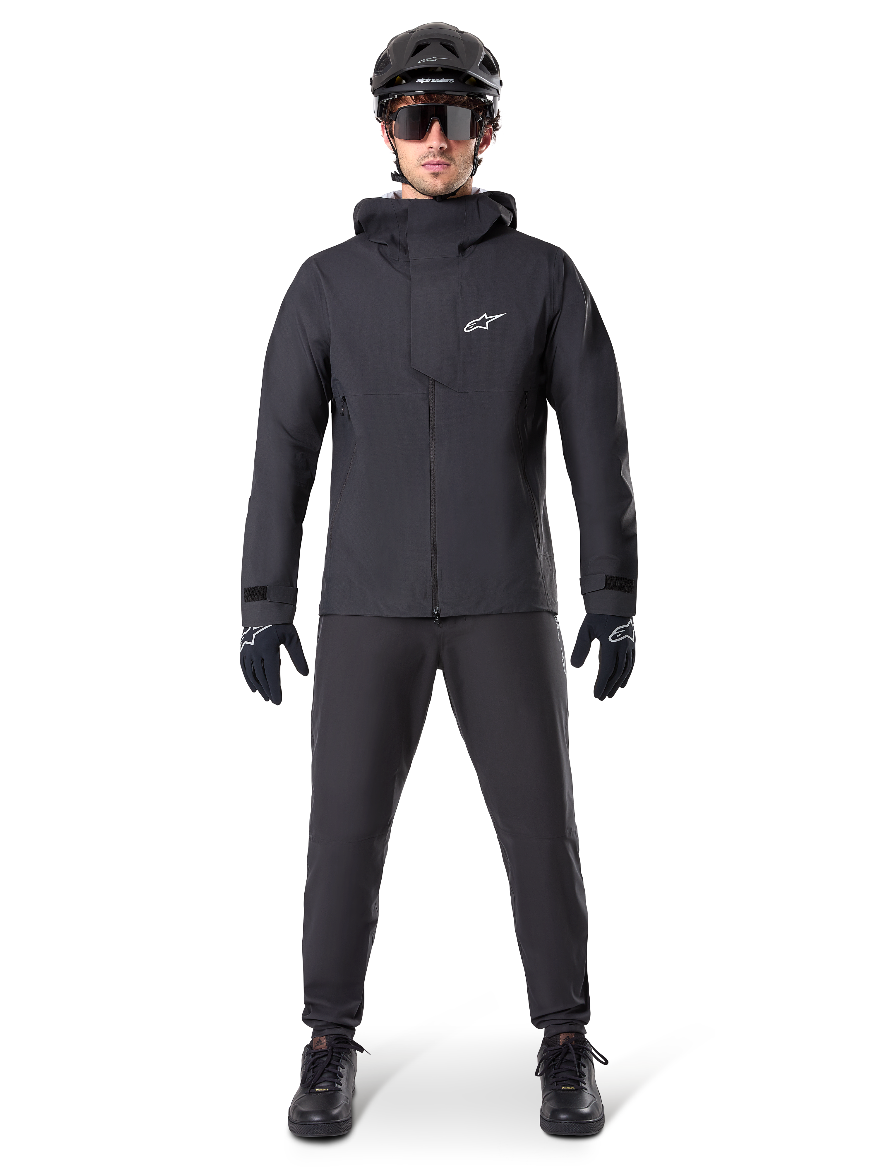 Alpinestars A-Dura Elite Waterproof Jacket, Black, worn with matching cycling pants and gloves, black helmet and sunglasses, featuring a white Astars logo on the chest, high-performance technical design for mountain biking