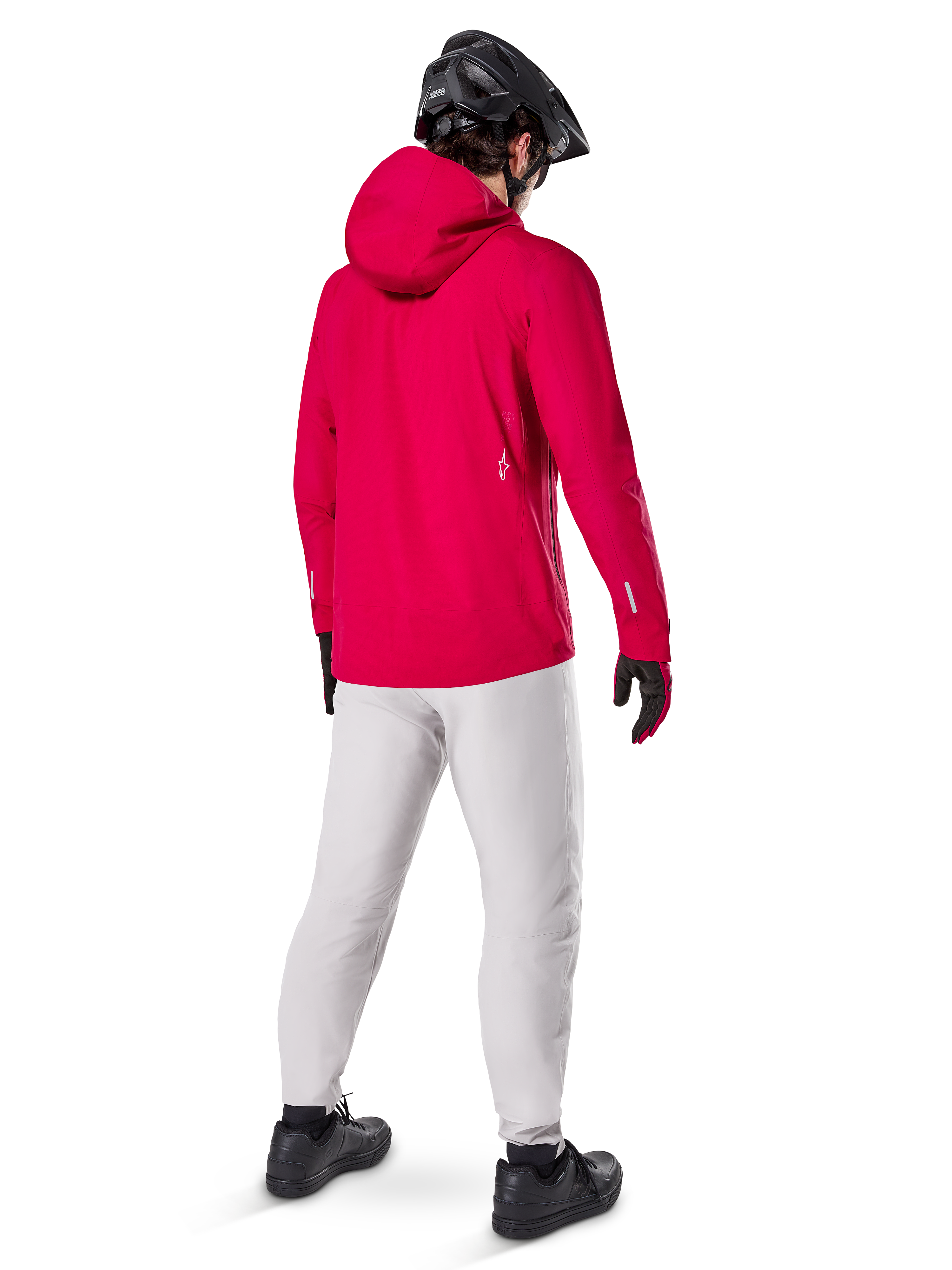 Alpinestars A-Dura Elite Wasserdichte Jacke, Red Fluo, Dreiviertel-Rückansicht, getragen mit hellgrauer Hose und schwarzem MTB-Helm, verfügt über eine Kapuze und reflektierende Akzente, Hochleistungs-Fahrrad-Regenjacke für Trailfahrten