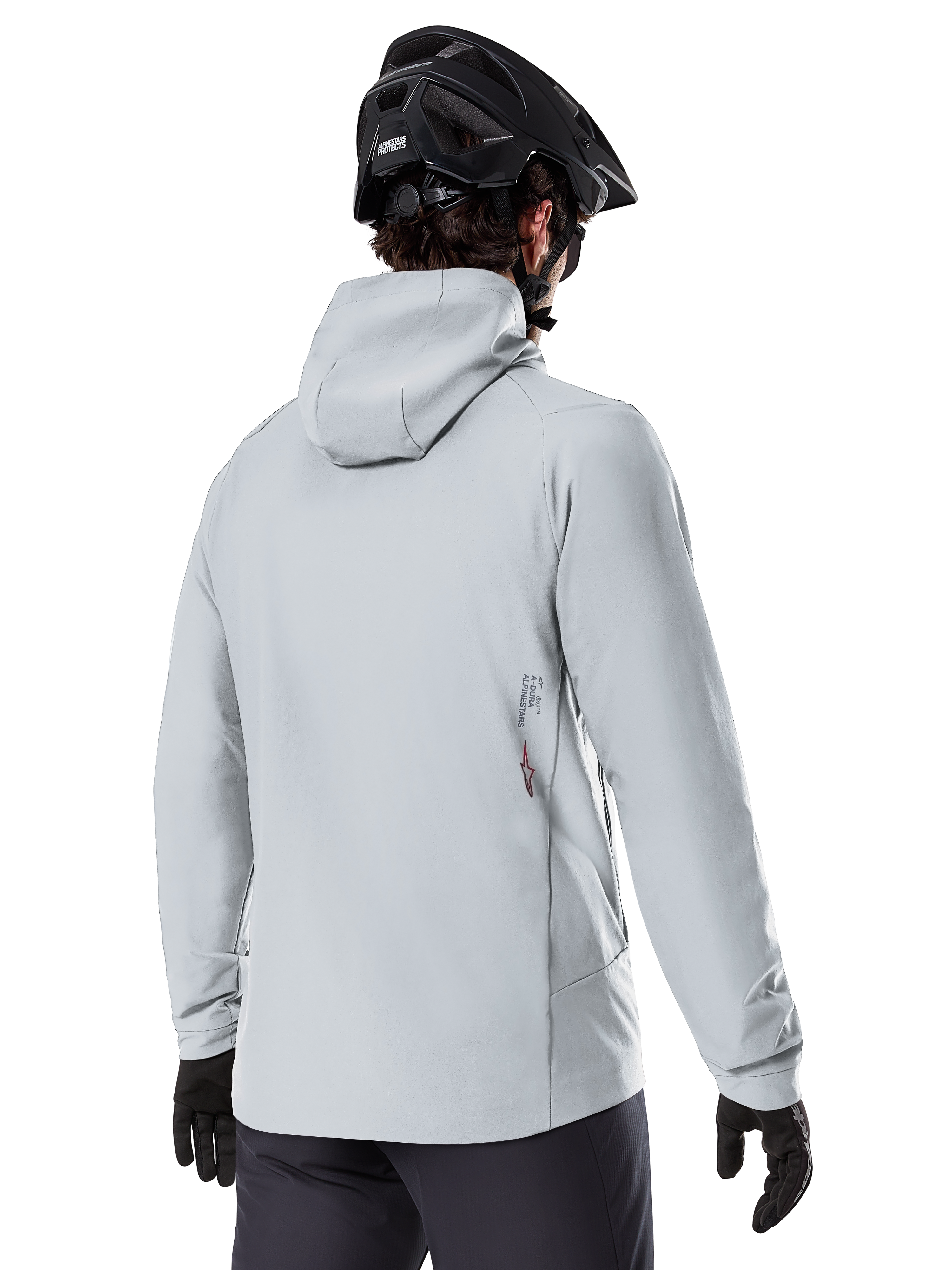 Alpinestars A-Dura Thermojacke, Titanium-Grau, Rückansicht eines Fahrers in der isolierten Kapuzenjacke, kombiniert mit einem schwarzen MTB-Helm und schwarzen Handschuhen, kleines Alpinestars-Logo am unteren Rücken, konzipiert für Mountainbiking bei kaltem Wetter