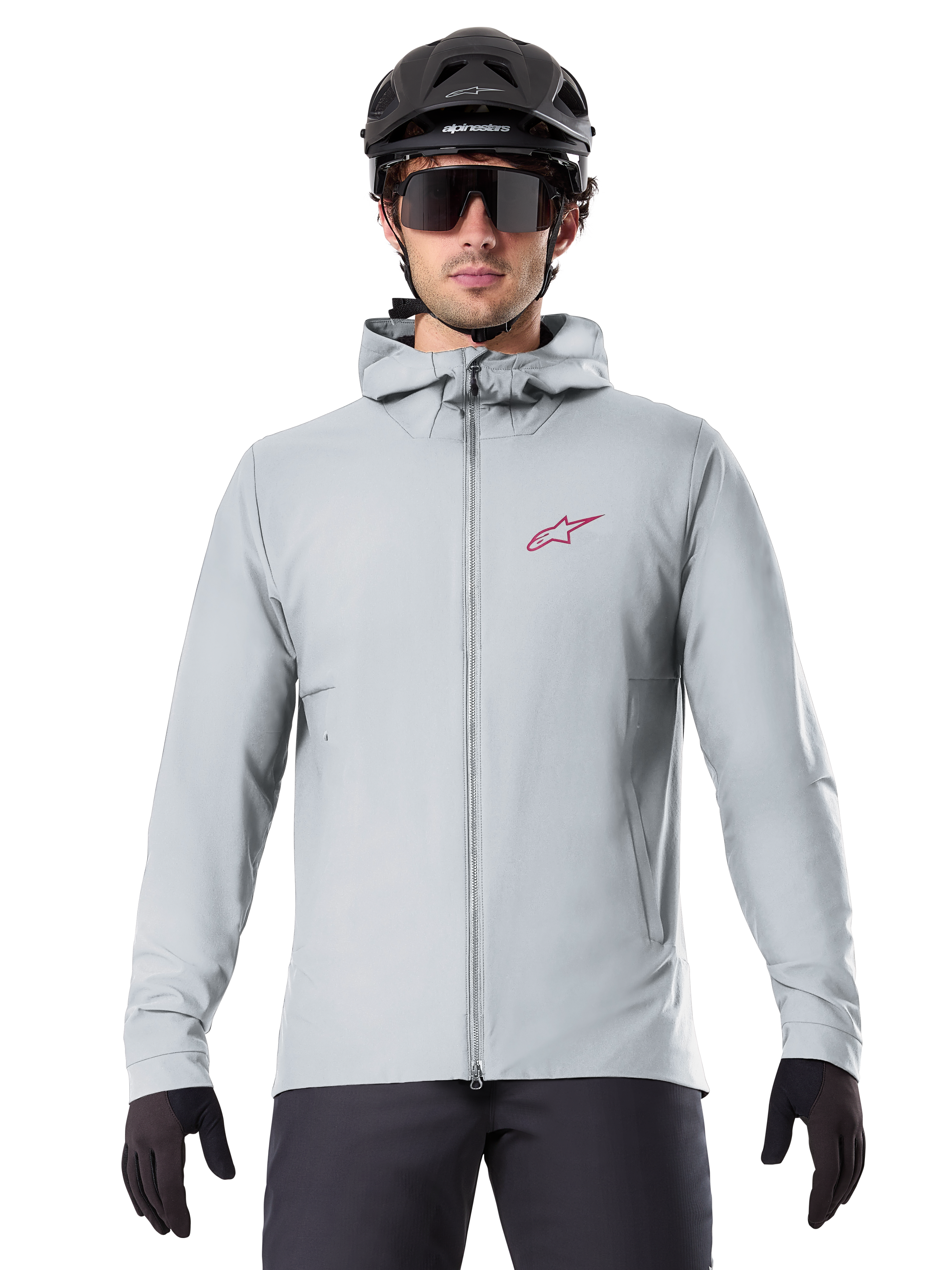 Alpinestars A-Dura Thermal Jacket in Titanium, hellgraue Fahrradjacke mit Kapuze und rotem Stern-Logo auf der Brust, getragen von einem Fahrer mit schwarzem MTB-Helm, Sonnenbrille und Handschuhen, isolierte Ausrüstung fürs Mountainbiken