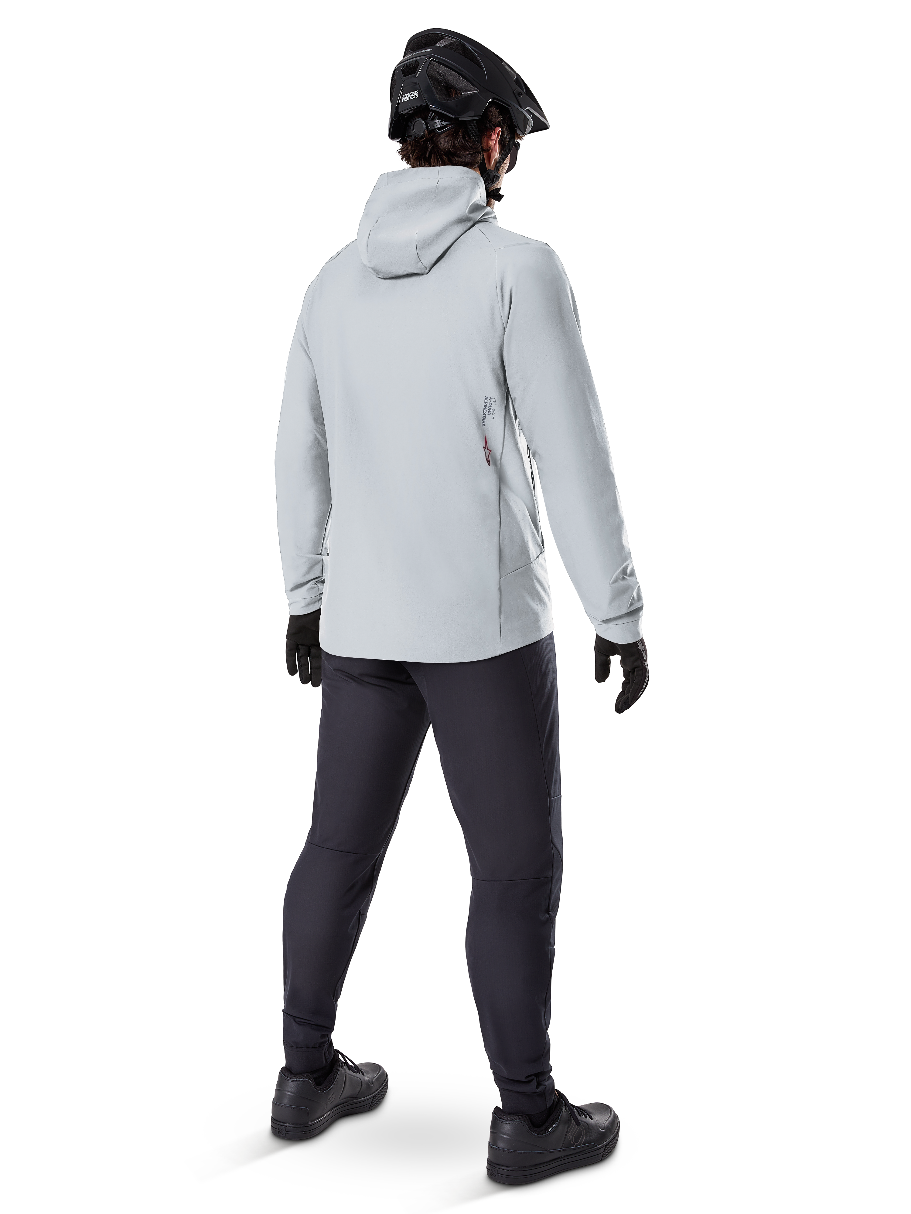 Alpinestars A-Dura Thermojacke in Titanium, Rückansicht eines männlichen Radfahrers in hellgrauer Thermojacke mit Kapuze, kombiniert mit schwarzem MTB-Helm, schwarzen Handschuhen und dunkelgrauer Hose, funktionelle Mountainbike-Ausrüstung