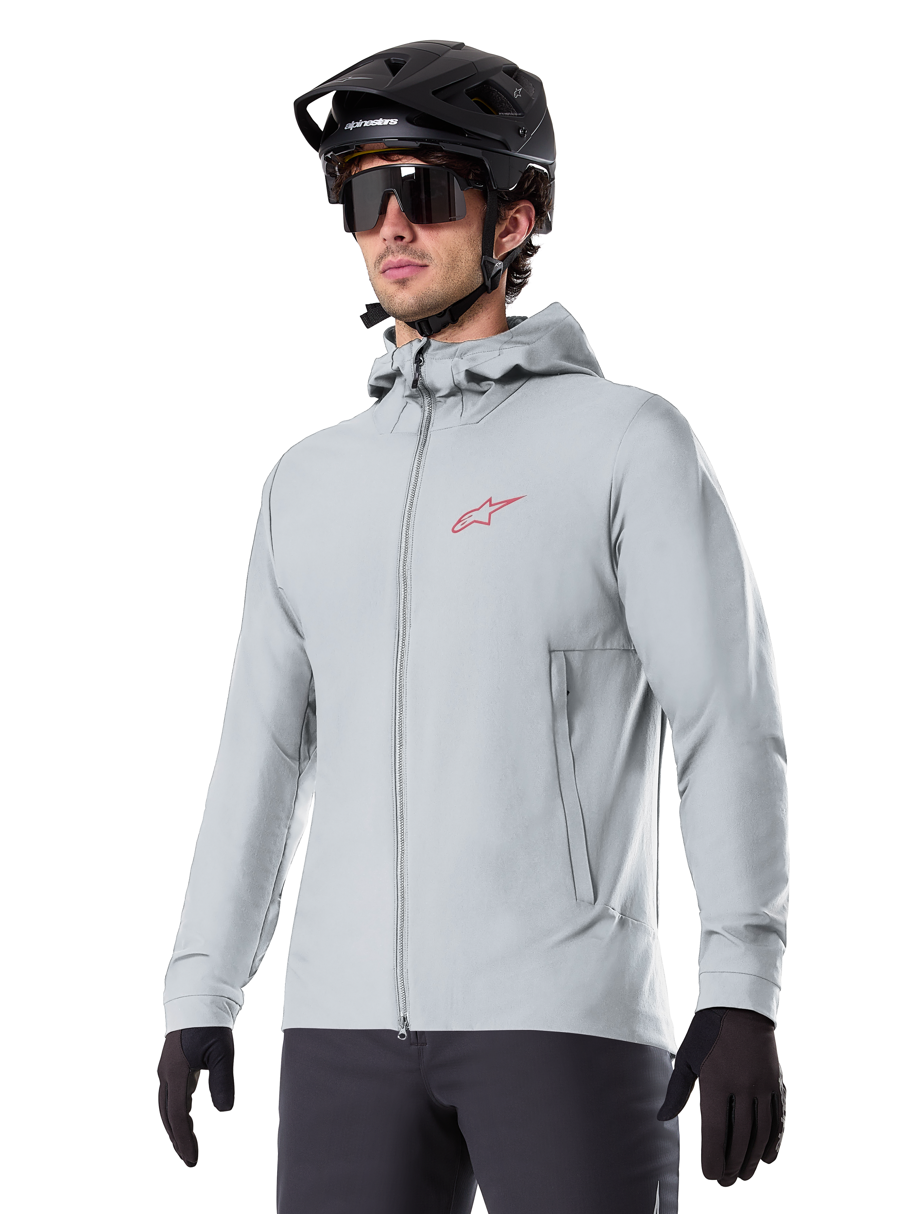 Alpinestars A-Dura Thermojacke, hellgraue isolierte Fahrradjacke, Kapuzendesign mit kleinem rotem Logo, getragen mit schwarzem Helm und Handschuhen, technische Mountainbike-Bekleidung für Fahrten bei kaltem Wetter
