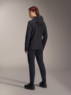 Alpinestars Stella A-Dura Thermal Jacket, MTB-Fahrradjacke für Damen, Schwarz, Rückansicht mit Fokus auf die isolierte Kapuze und die reguläre Passform, getragen mit passender schwarzer Hose und Schuhen, leichte Wärmeisolierung für Fahrten bei kaltem Wetter