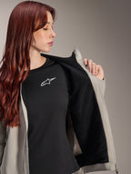 Frau in der Alpinestars Stella A-Dura Thermal Jacke in Titanium, zeigt das schwarze, strukturierte Fleece-Futter, getragen über einem schwarzen T-Shirt mit weißem Stern-Logo, leichte Mountainbike-Jacke für kalte Bedingungen.