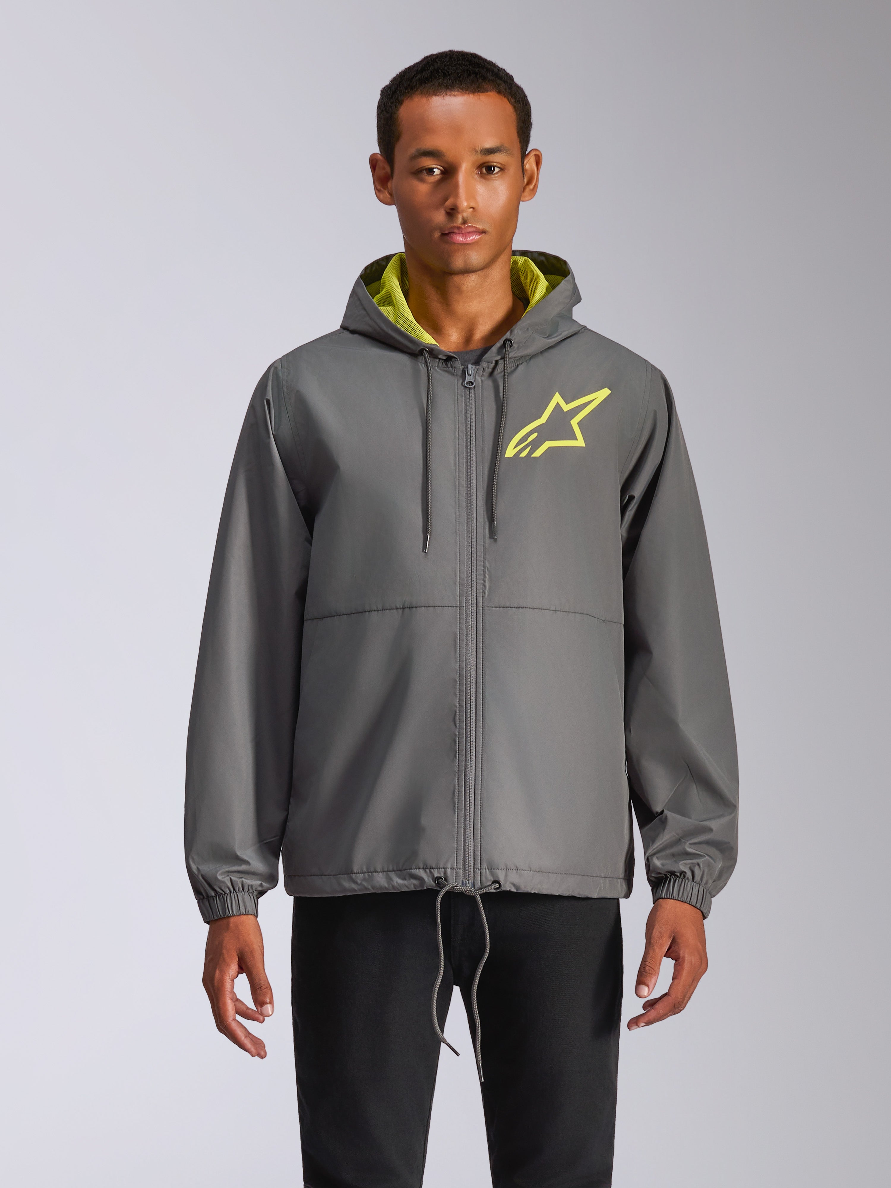 Alpinestars Speeder Chromium Windbreak Jacket, anthrazitgraue Windjacke mit Kapuze, neongelbes Stern-Logo, hellgrünes Kapuzenfutter, elastische Bündchen, verstellbare Kordelzüge, Frontreißverschluss, lässiger Motorsport-Stil