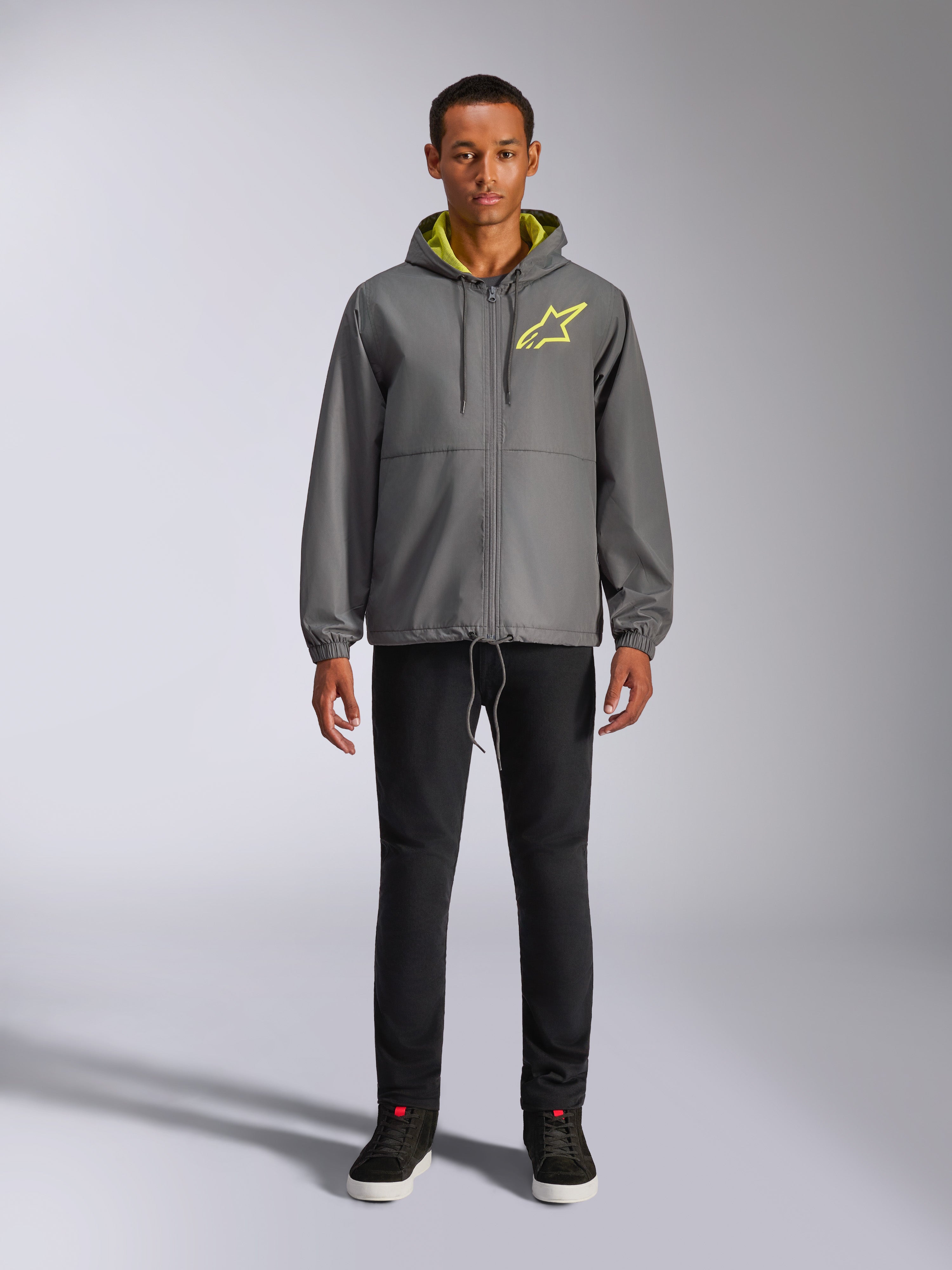 Alpinestars Speeder Chromium Windbreak Jacke, anthrazitgraue Kapuzenjacke mit neongelbem Innenfutter und Logo auf der Brust, durchgehender Frontreißverschluss, elastische Bündchen, lässige, vom Motorsport inspirierte Streetwear