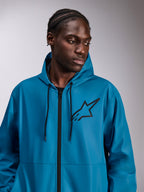 Männliches Model trägt die Alpinestars Speeder Chromium Windbreaker-Jacke, Blau, leichte Windjacke mit Kapuze, schwarzes Astars-Logo auf der Brust, schwarzer Frontreißverschluss und Kordelzüge, lässige Streetwear im Motorsport-Stil