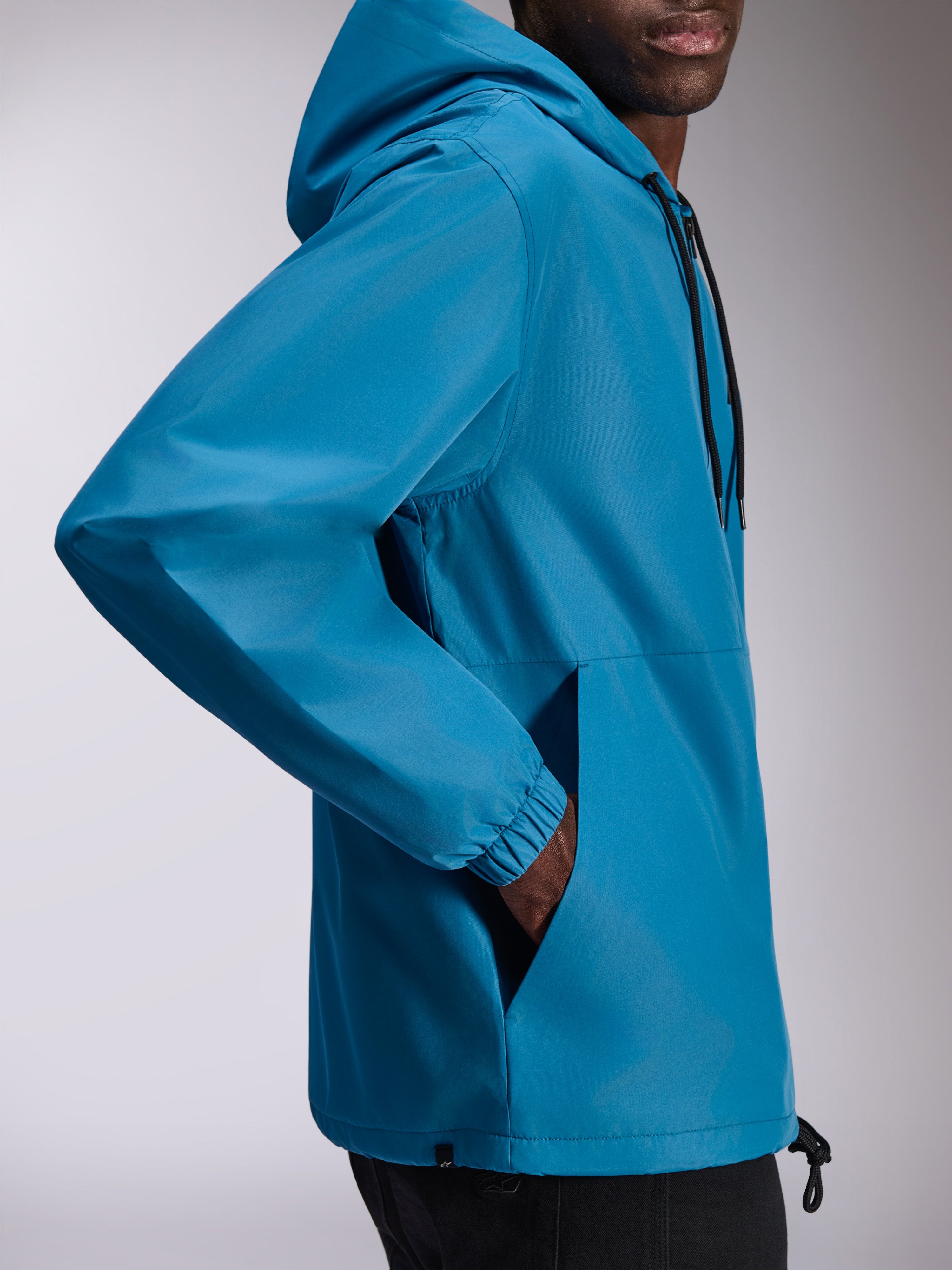 Alpinestars Speeder Chromium Windbreaker-Jacke, leichte Kapuzen-Windjacke in Blau, Seitenansicht mit elastischen Bündchen und Handtaschen, verstellbare Kapuze mit Kordelzug, lässiges, vom Motorsport inspiriertes Design