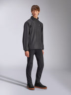 Alpinestars Overhaul Racer Jacke, schwarze Regenjacke, getragen mit schwarzer Hose und schwarzen Sneakern mit Gummisohlen, weißes Stern-Logo auf der Brust, Reißverschluss vorne, lässige vom Motorsport inspirierte Sportbekleidung