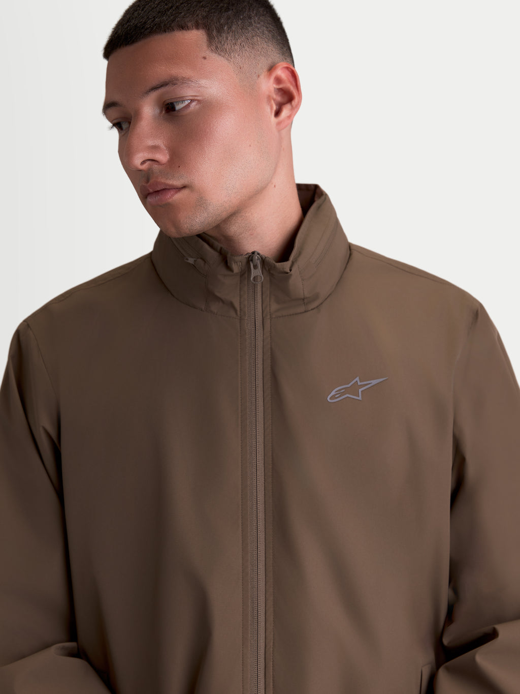 Alpinestars Overhaul Racer Jacke, Herren-Sportswear-Jacke in Walnussbraun, motorsport-inspiriertes Design mit hohem Kragen, verstaubarem Kapuzenfach und kleinem HD-Print-Logo auf der Brust.