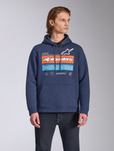 Alpinestars Harken Hoodie, lässige Streetwear, Navyblau mit „Racing Ahead“-Grafik auf der Brust in Orange und Hellblau, Fleece-Kapuzenpullover mit Kängurutasche und Kapuze mit Kordelzug, getragen von einem Model mit dunkler Jeans
