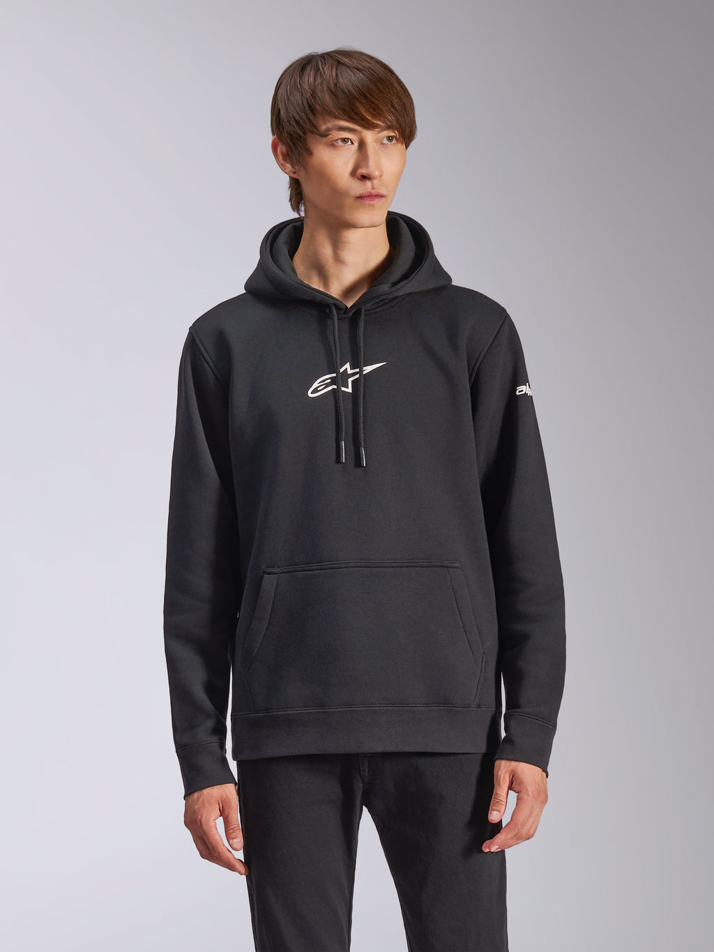 Alpinestars Frontal Hoodie, schwarzer Fleece-Kapuzenpullover, weißes Alpinestars-Logo auf der Brust, weißer Schriftzug am Ärmel, Kängurutasche, lässige Motorsport-Streetwear