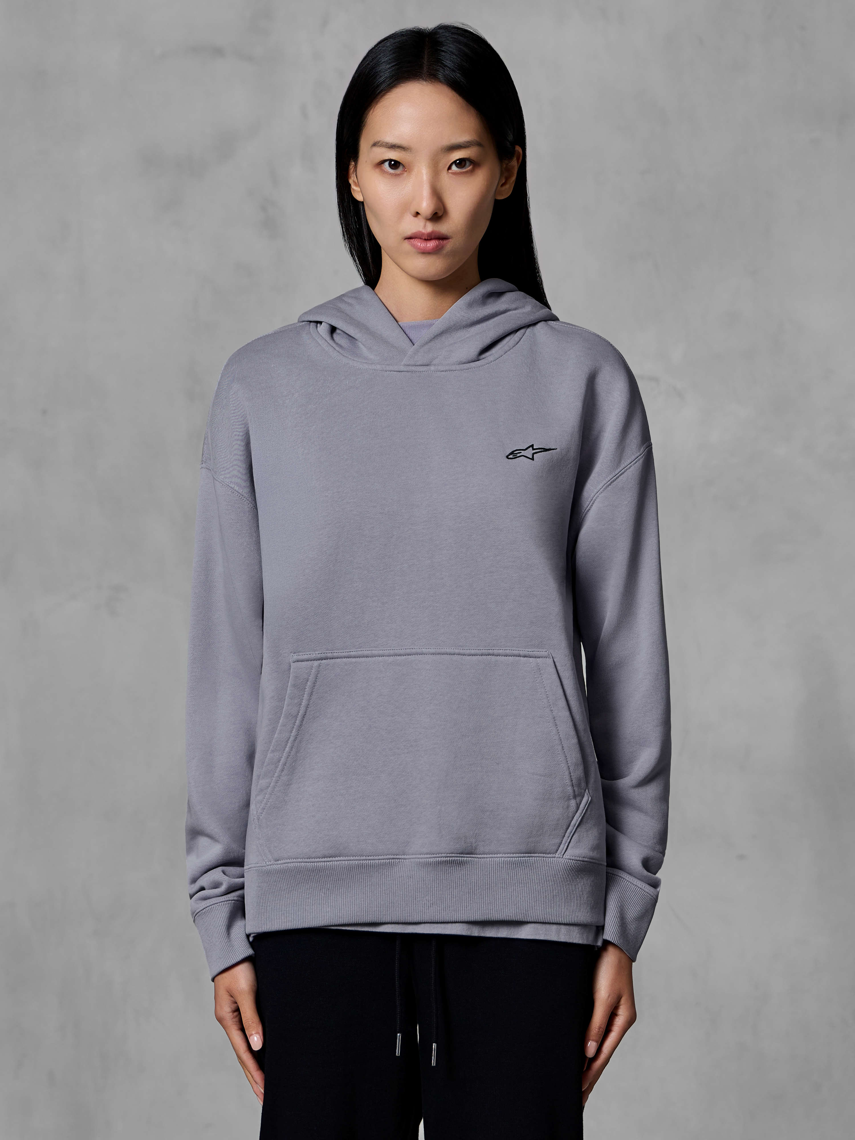 Alpinestars Essentials Ageless Hoodie, lässige Sportbekleidung, Silber mit kleinem schwarzem Logo, Kängurutasche, Kapuzenpullover, von einem Model getragen, moderne Lifestyle-Bekleidung