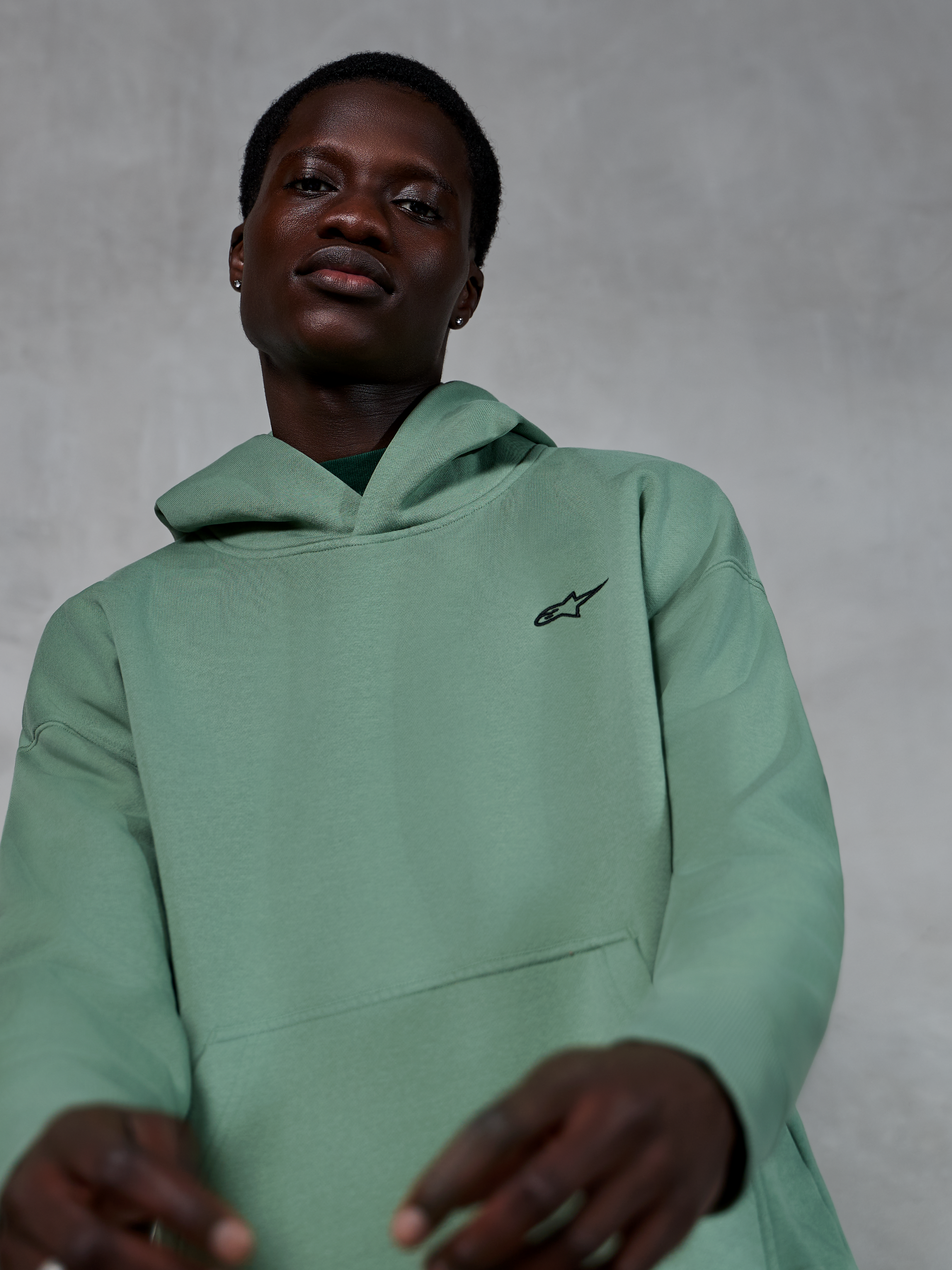 Alpinestars Essentials Ageless Hoodie, casual sportswear in Cactus green, worn by a model, featuring a small black Alpinestars logo on the chest, high-quality fleece with a relaxed fit and clean aesthetic.