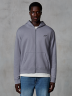 Alpinestars Essentials Ageless Zip Hoodie, Silber, lässige Streetwear von einem Model getragen, Fleece-Jacke mit durchgehendem Reißverschluss und kleinem schwarzen Astars-Logo auf der Brust, Kängurutaschen, entspannte Passform