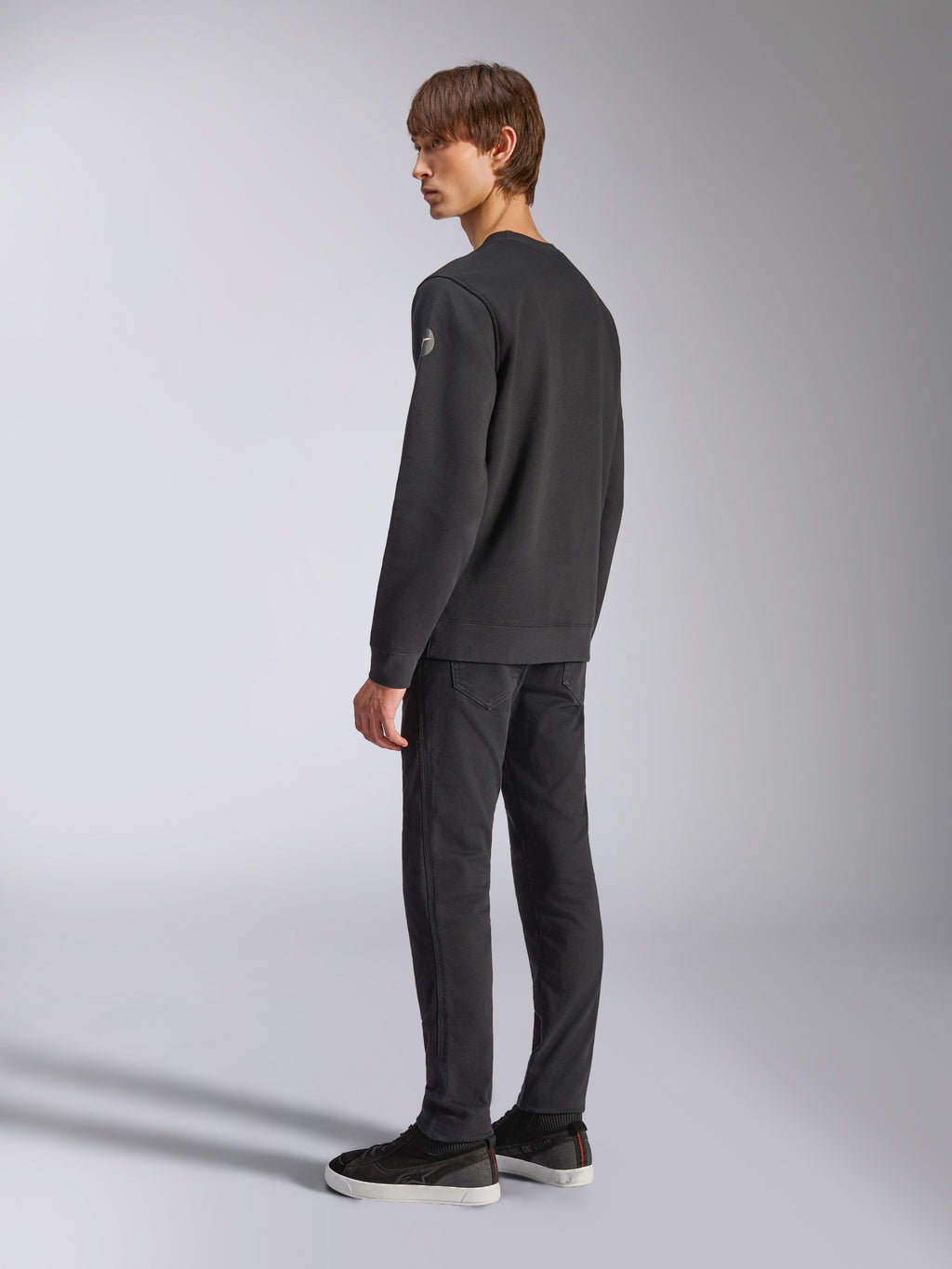 Alpinestars Bettern Crew, Fleece-Pullover, Schwarz, männliches Model in Rück- und Seitenansicht, mit gerippten Bündchen und Saum sowie einem kleinen Logo am Ärmel, lässige, vom Motorsport inspirierte Streetwear