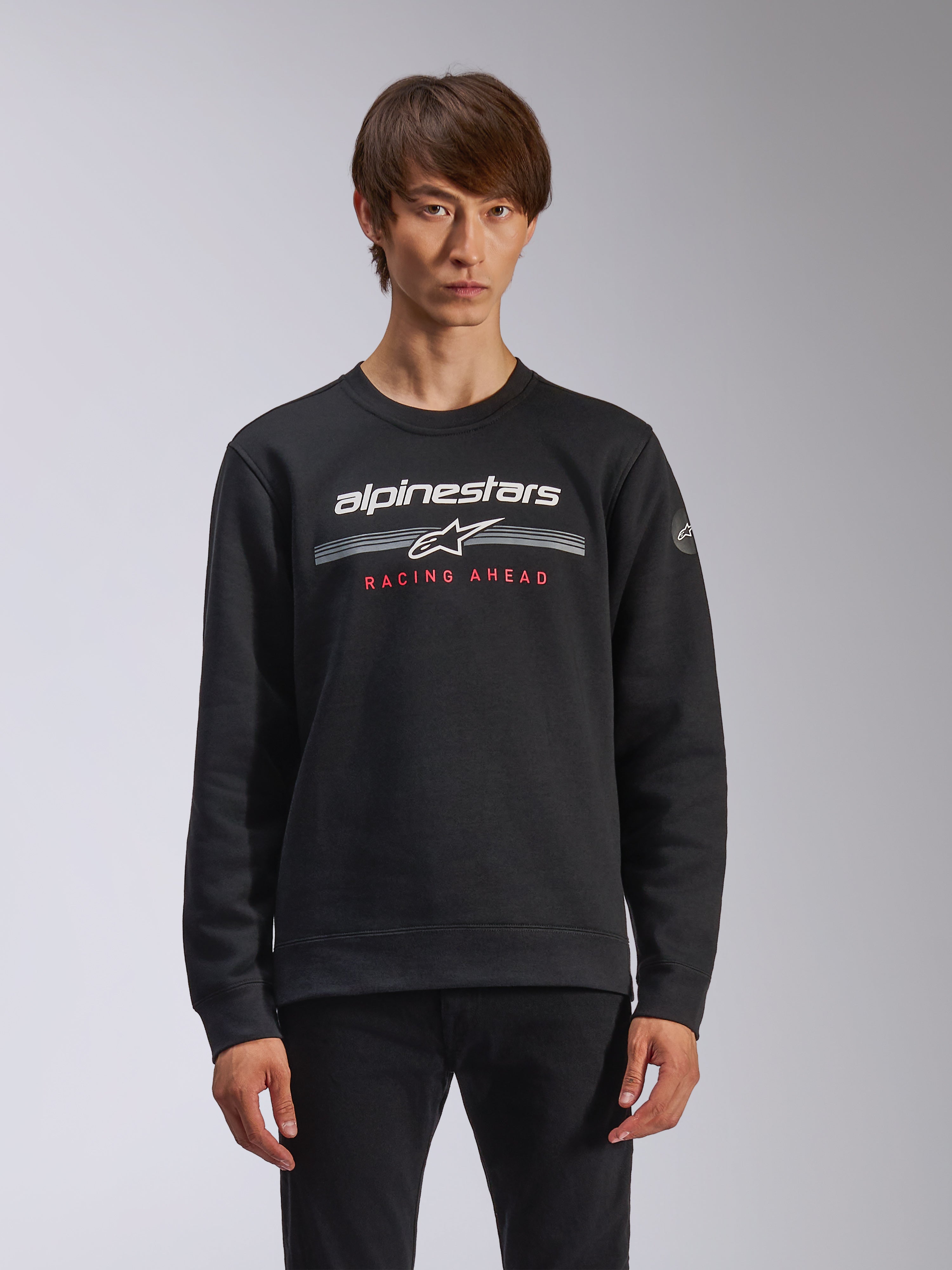 Alpinestars Bettern Crew, Sweatshirt mit Rundhalsausschnitt, Schwarz, mit weißem Alpinestars-Branding, horizontalen grauen Streifen und rotem „RACING AHEAD“-Schriftzug, lässige Motorsport-Streetwear
