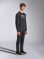 Alpinestars Bettern Crew Sweatshirt, schwarzer Rundhals-Pullover, weißes Alpinestars-Logo mit „RACING AHEAD“ in Rot auf der Brust, kombiniert mit schwarzer Hose und Sneakern, lässige, vom Motorsport inspirierte Streetwear