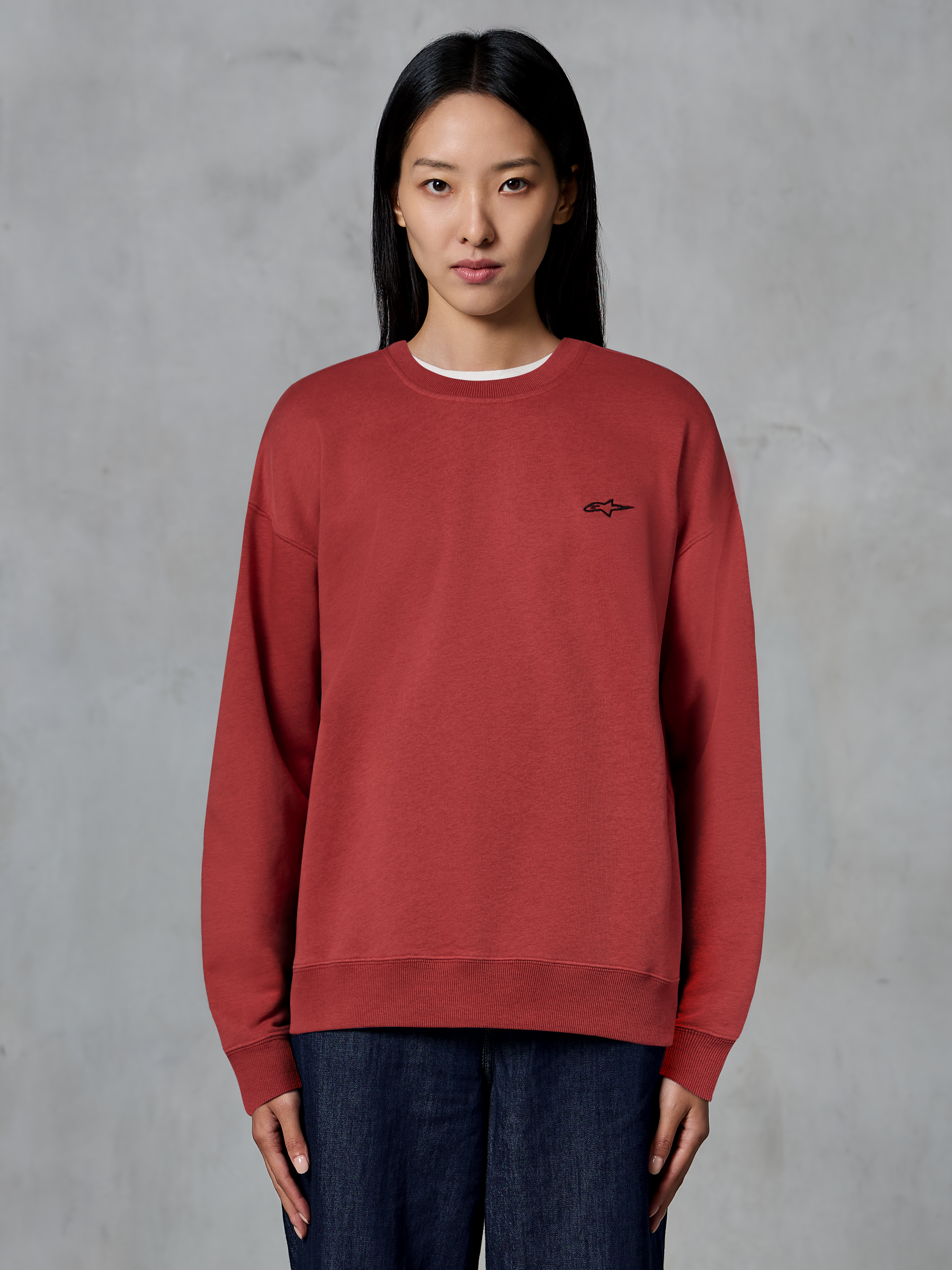 Alpinestars Essentials Ageless Crew, Brick Red crewneck sweatshirt, small black logo on chest, premium fleece, worn by model, casual motorsport-inspired streetwear