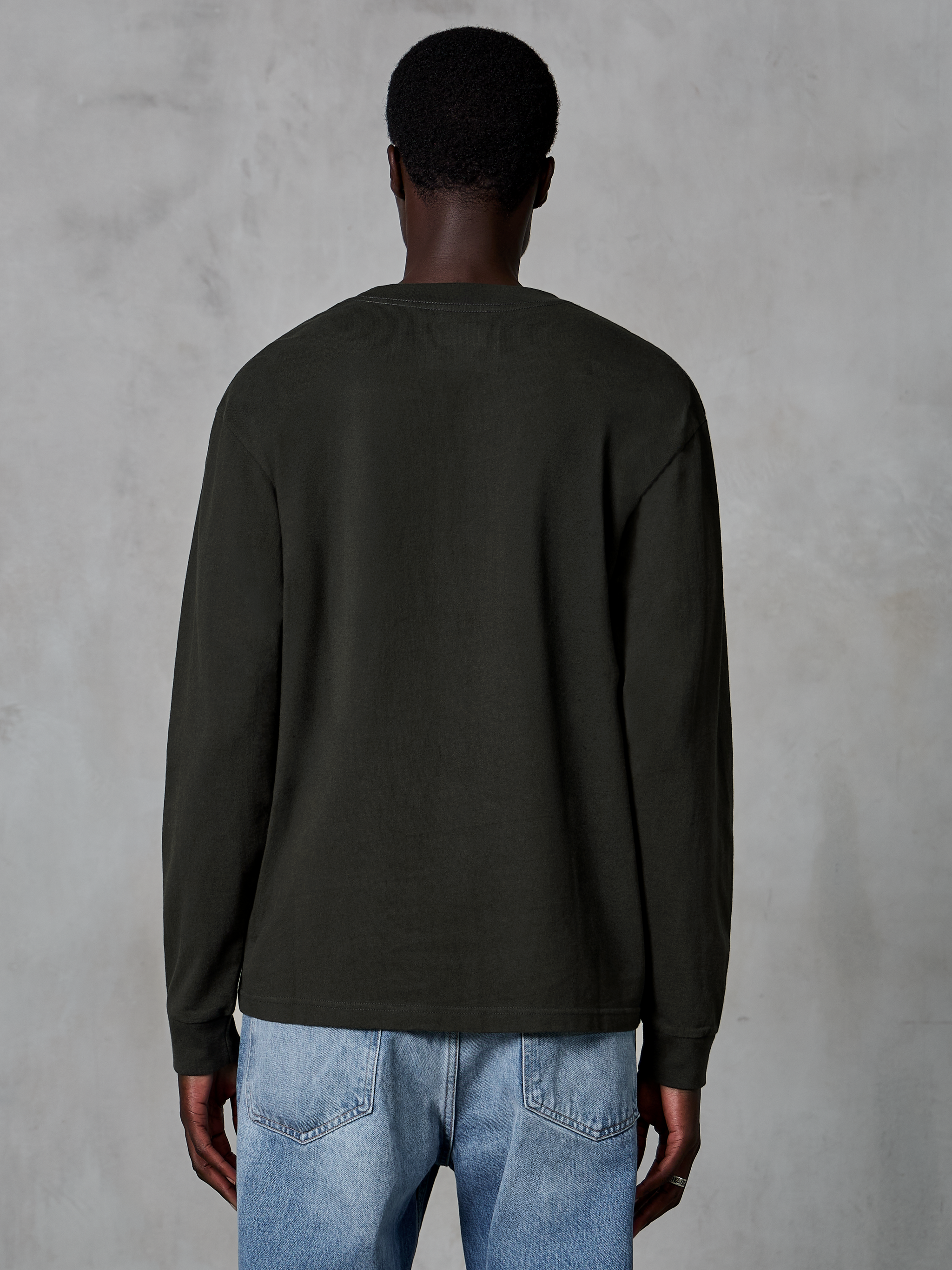 Alpinestars Essentials Ageless LS Tee, Langarm-T-Shirt, Off Black, Rückansicht zeigt klares Design und entspannte Passform, getragen von Model mit blauen Jeans, lässige Motorsport-inspirierte Streetwear