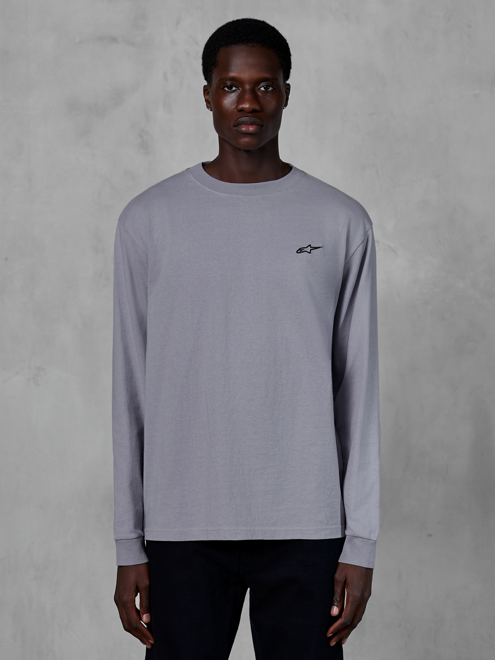 Alpinestars Essentials Ageless LS Tee, Langarmshirt, Silber, von einem Model getragen, mit kleinem schwarzem Alpinestars-Logo auf der Brust, entspannte zeitgemäße Passform, lässige Streetwear aus Bio-Baumwolle