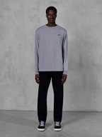 Alpinestars Essentials Ageless LS Tee, Langarm-T-Shirt, Silber, kleines schwarzes Alpinestars-Logo auf der Brust, Bio-Baumwolljersey mit Stone-Wash-Finish, getragen von einem Model mit schwarzer Hose und Sneakern, lässige Streetwear