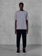Alpinestars Essentials Ageless SS Tee, Kurzarm-T-Shirt, Silber, mit einem kleinen schwarzen Logo auf der Brust, kombiniert mit schwarzen Jogginghosen und Sneakern, lässige Motorsport-Streetwear