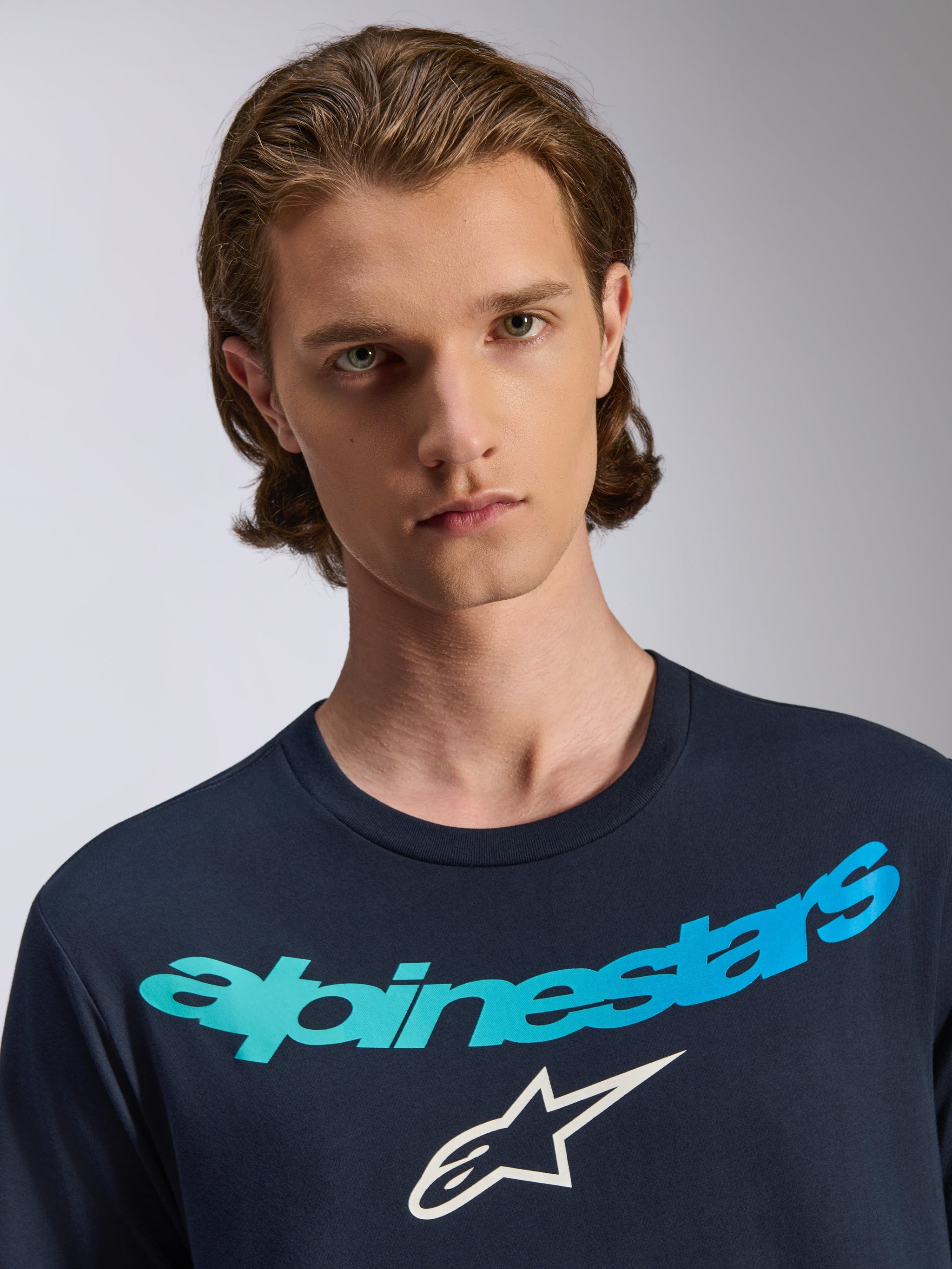 Alpinestars Collared CSF T-Shirt, kurzärmeliges T-Shirt, Marineblau, mit Alpinestars-Logo in Blau-Türkis-Farbverlauf und weißem Stern-Emblem, lässige Performance-Sportbekleidung, getragen von einem männlichen Model